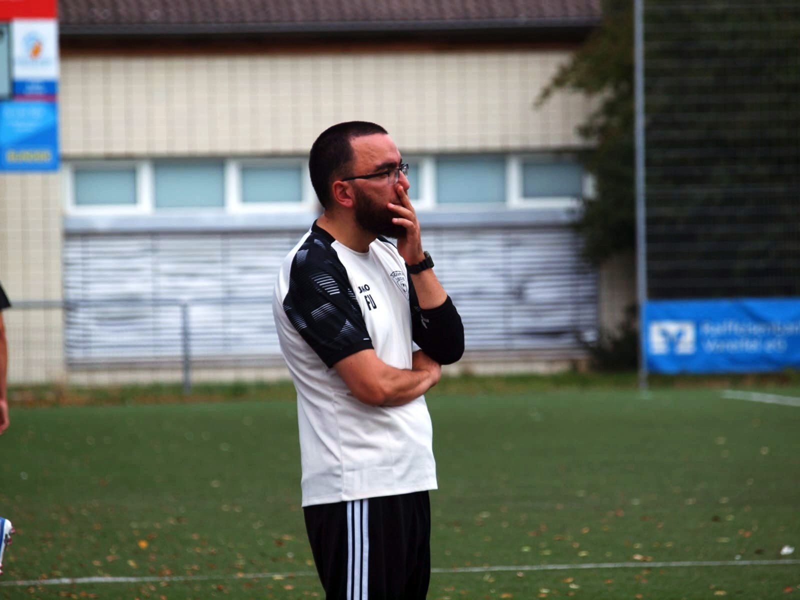 Firat Uyar beobachtet ein Spiel seiner Mannschaft, seine linke Hand liegt vor seinem Mund.