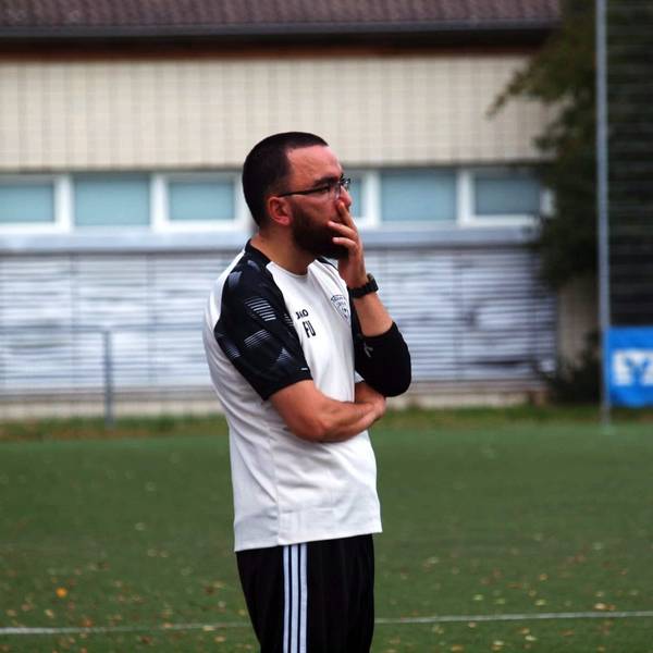 Firat Uyar beobachtet ein Spiel seiner Mannschaft, seine linke Hand liegt vor seinem Mund.