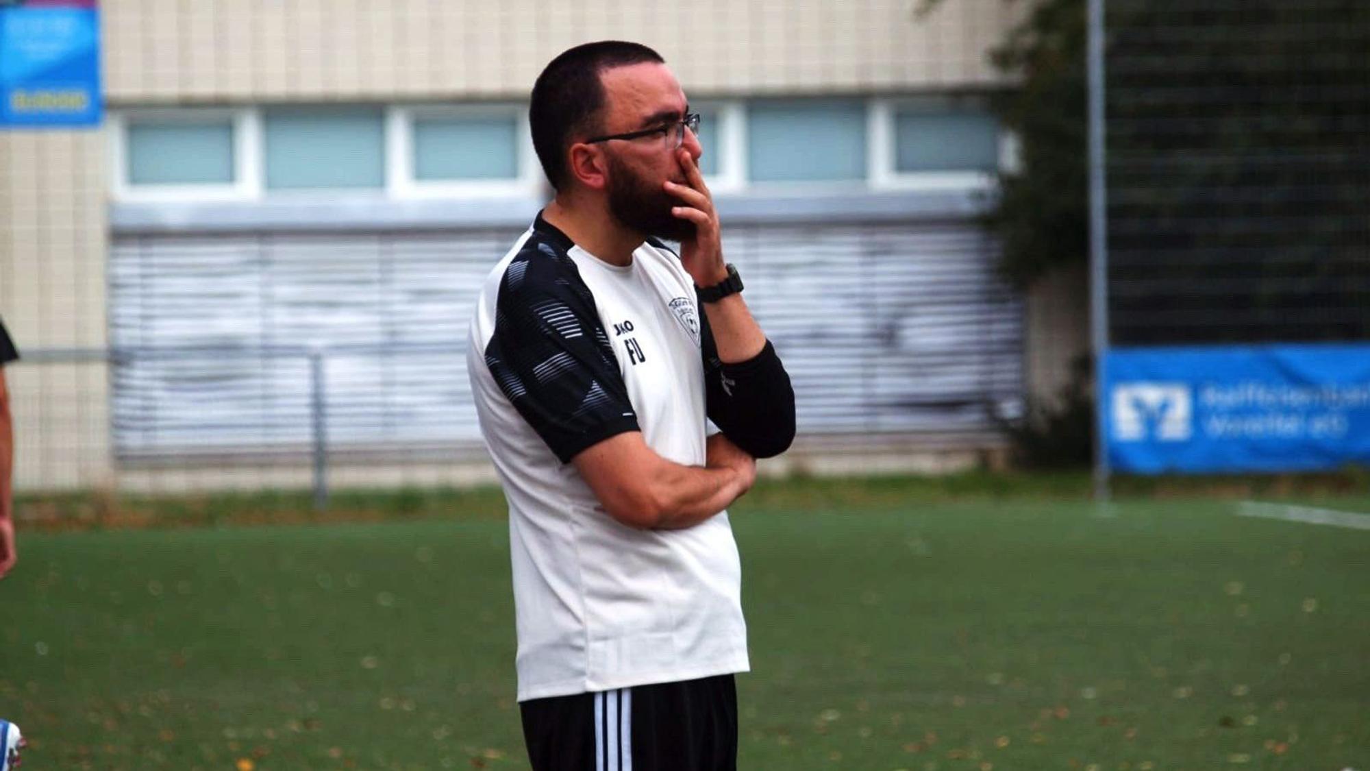Firat Uyar beobachtet ein Spiel seiner Mannschaft, seine linke Hand liegt vor seinem Mund.