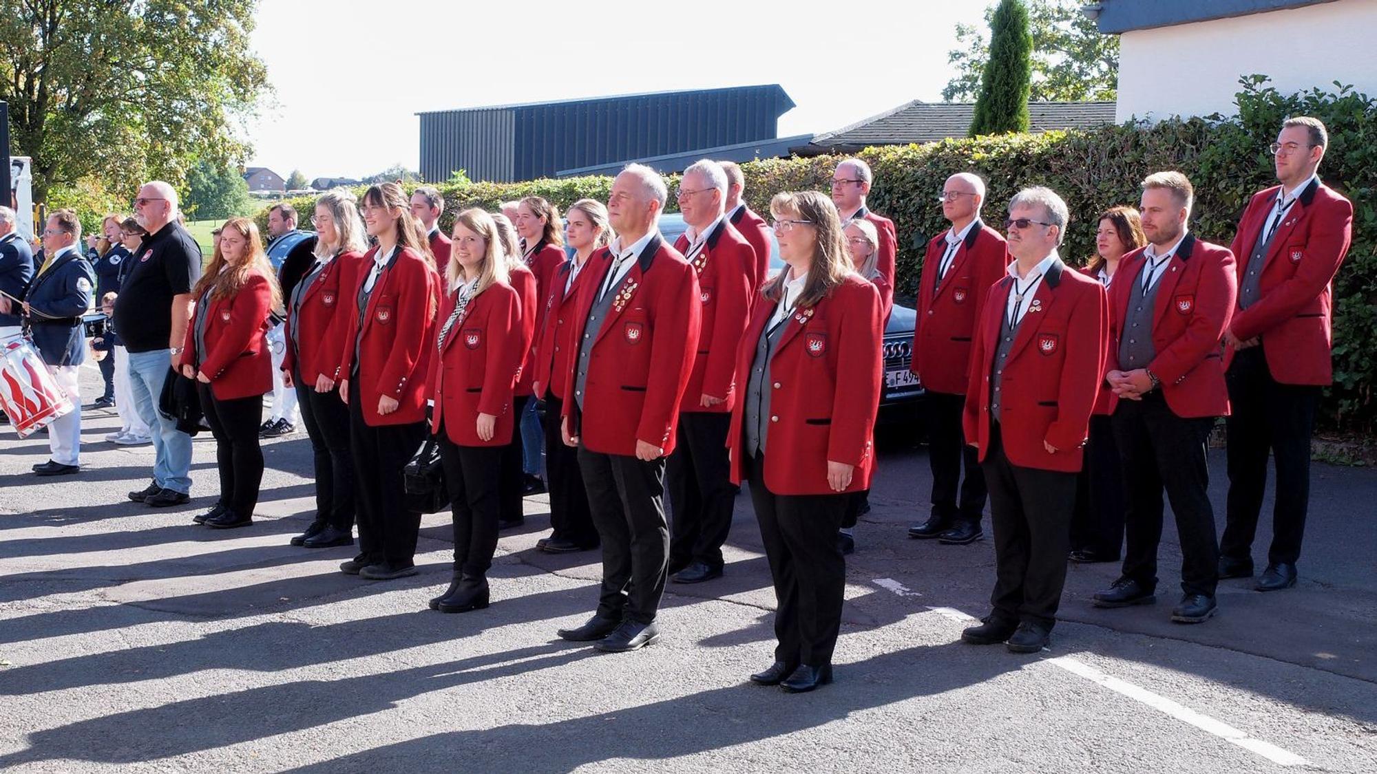 Die Mitglieder des Musikvereins Eifelklänge stehen aufgereiht auf der Straße.