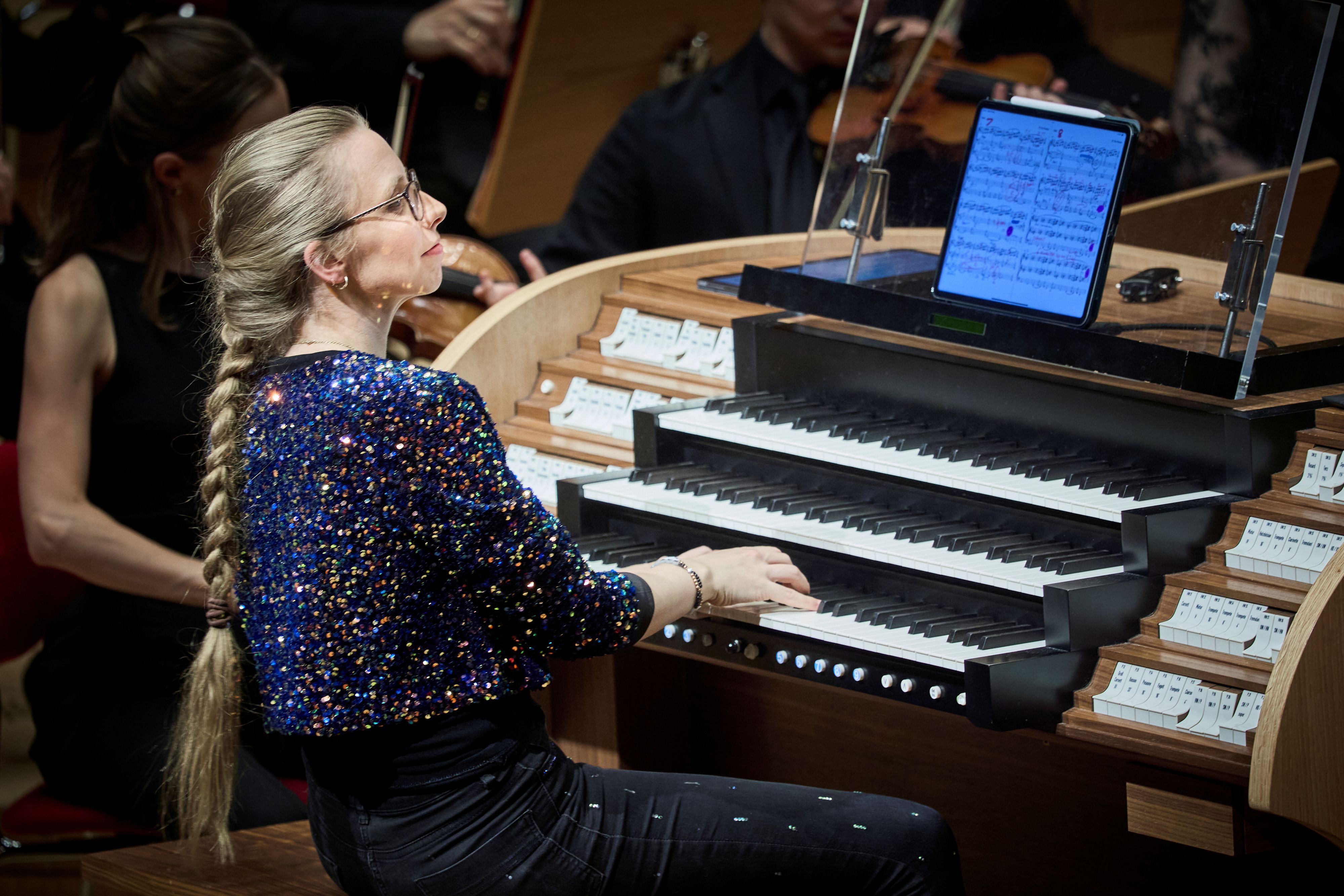 Eine Frau im glitzernden Oberteil sitzt an der Orgel.