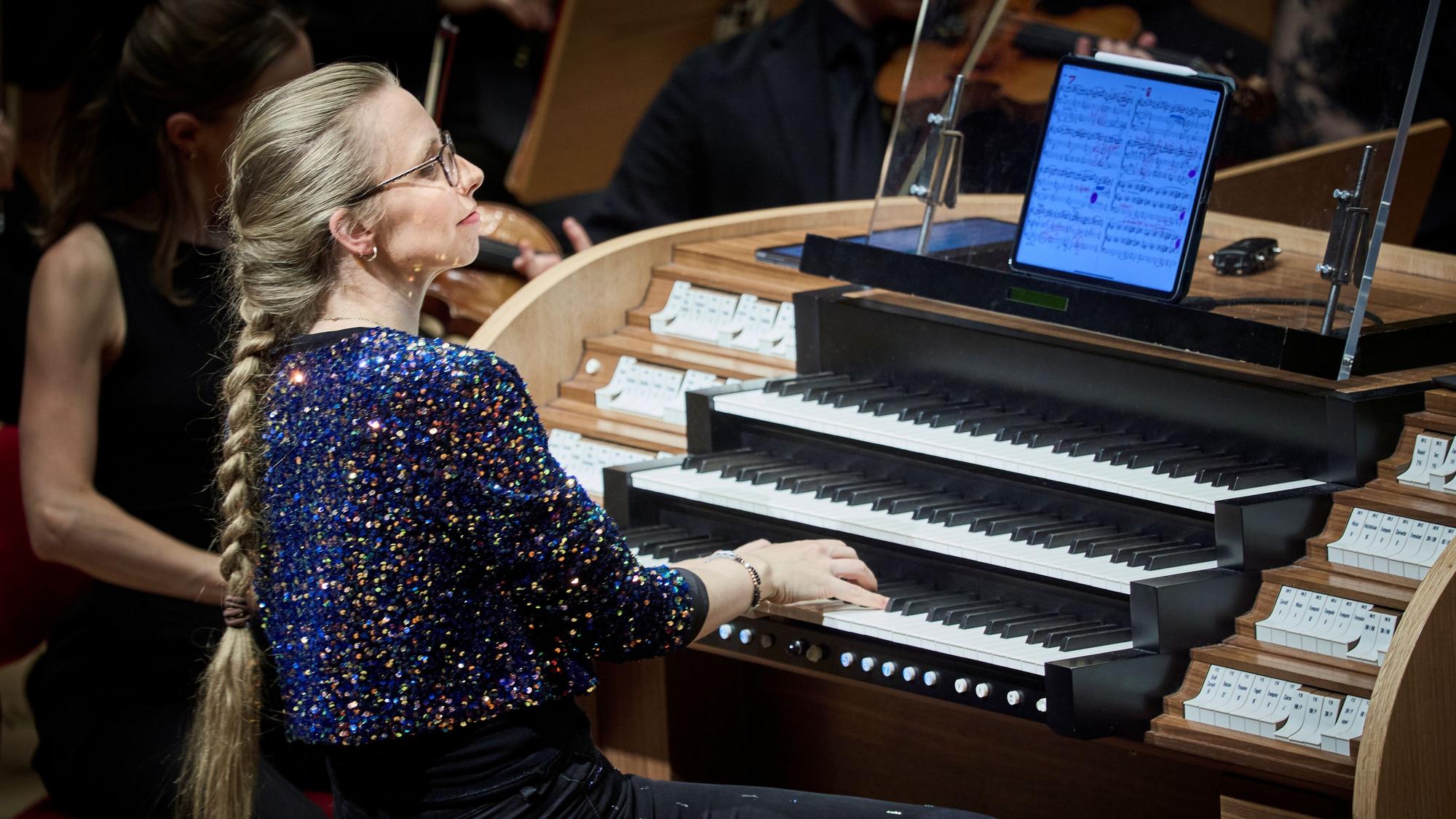 Eine Frau im glitzernden Oberteil sitzt an der Orgel.