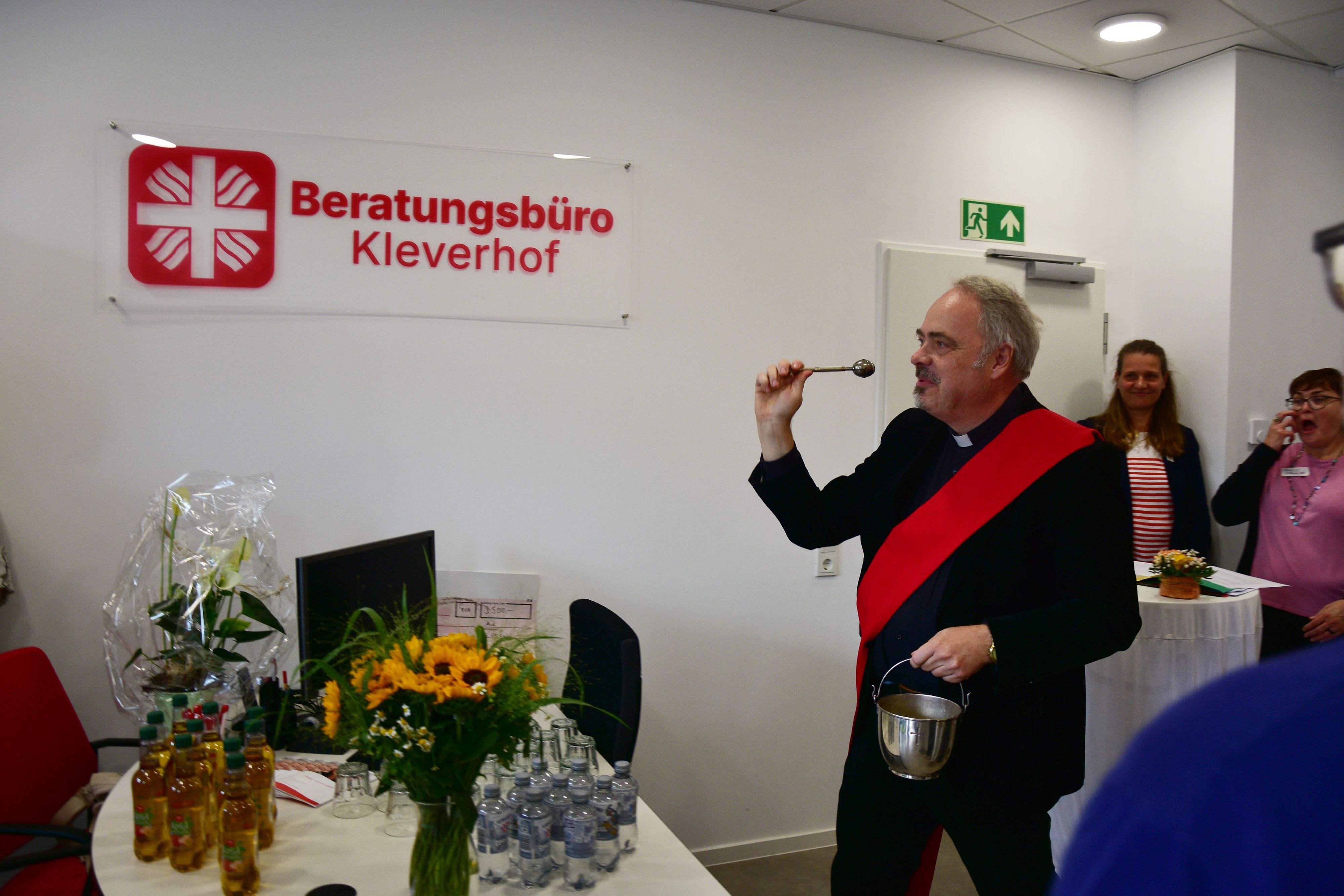 Ein Geistlicher segnet Räume mit Weihwasser.