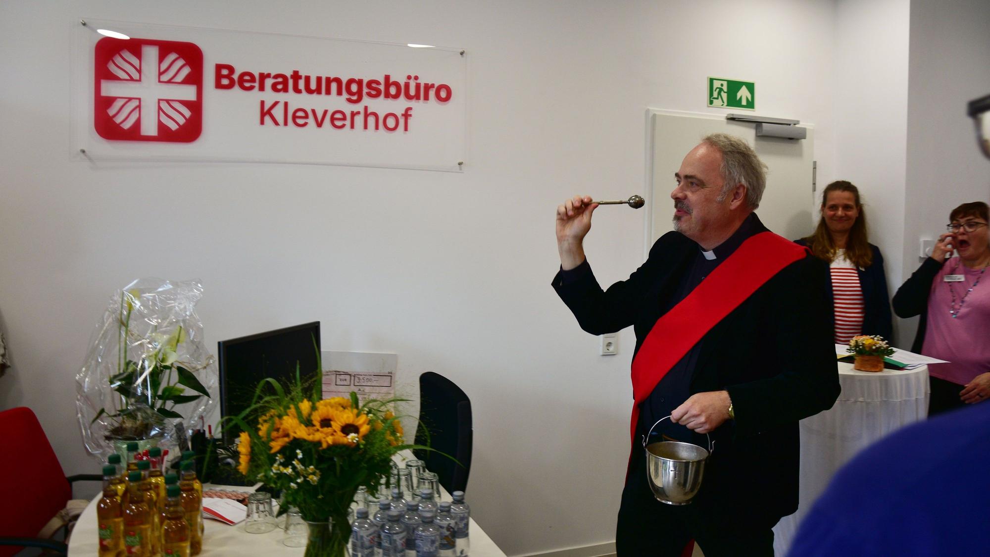 Ein Geistlicher segnet Räume mit Weihwasser.