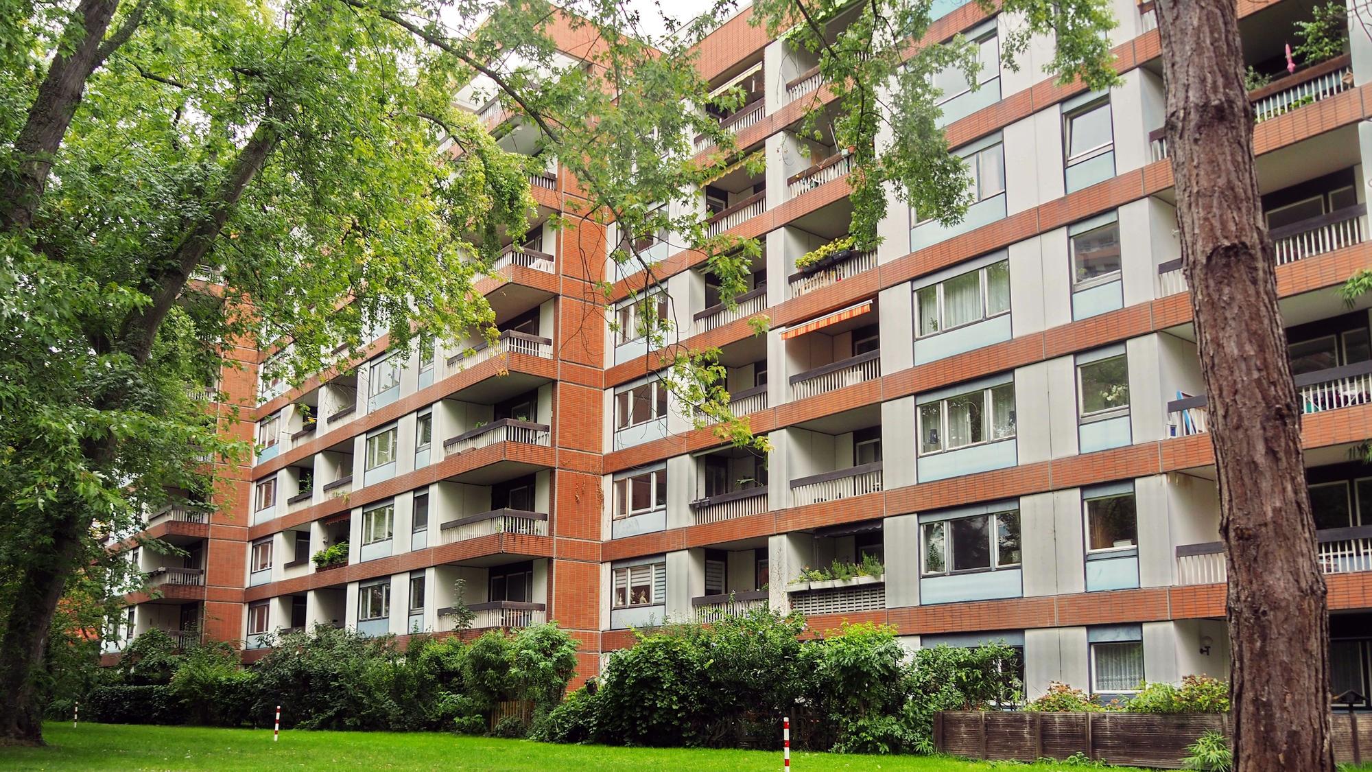 Mehrstöckige Wohnblocks stehen hinter einer Rasenfläche.