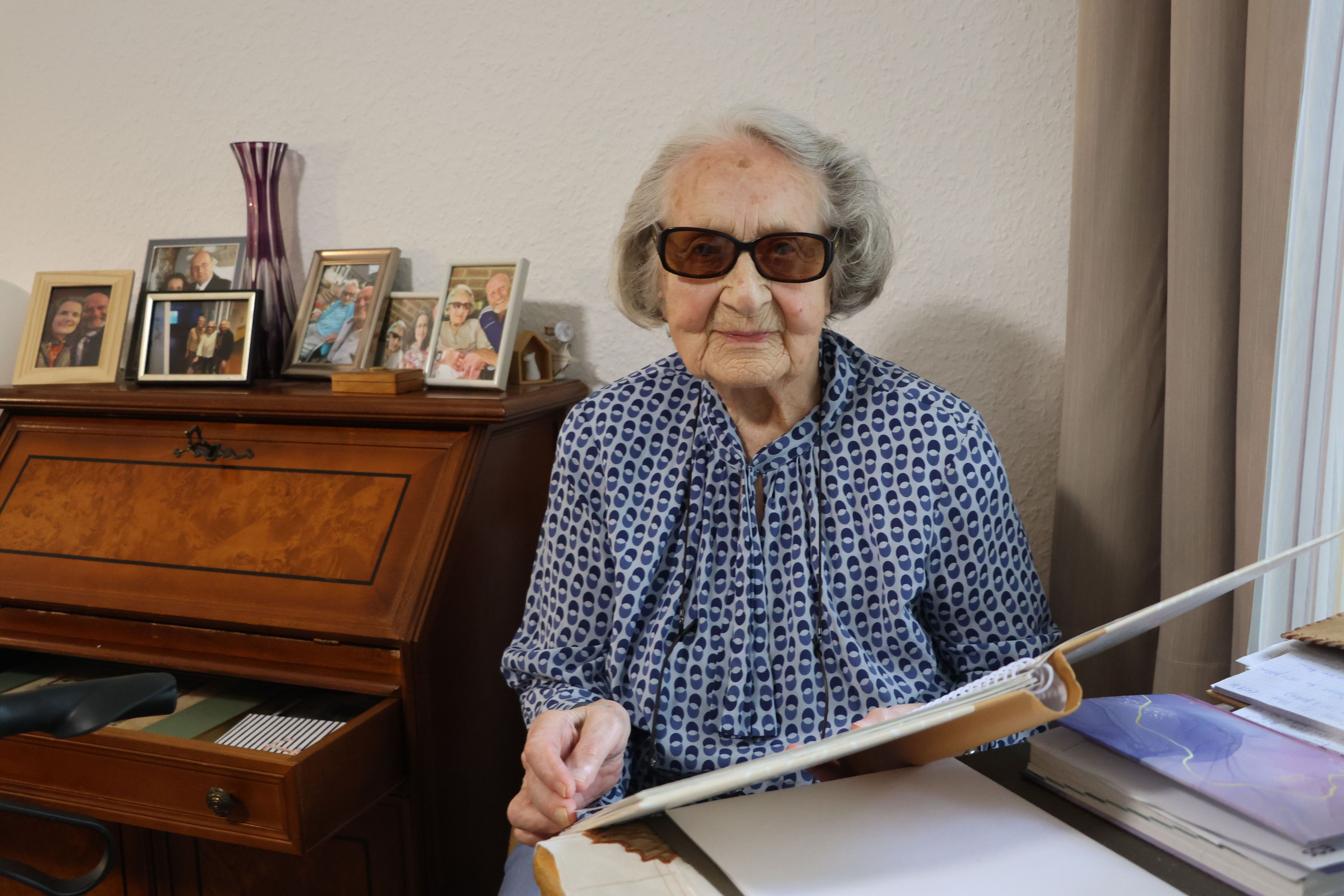Auf dem Bild ist eine Seniorin zu sehen, die in einem Album blättert.
