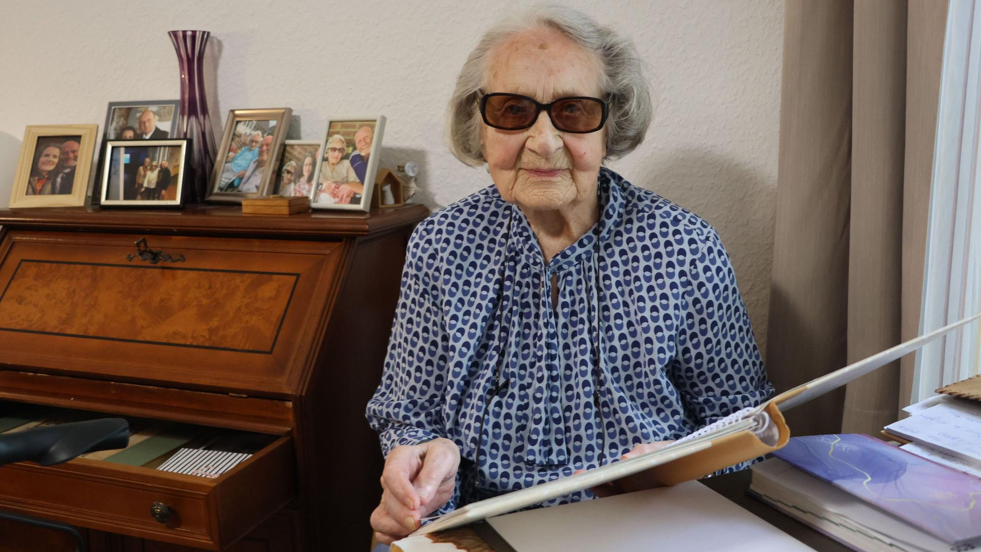 Auf dem Bild ist eine Seniorin zu sehen, die in einem Album blättert.