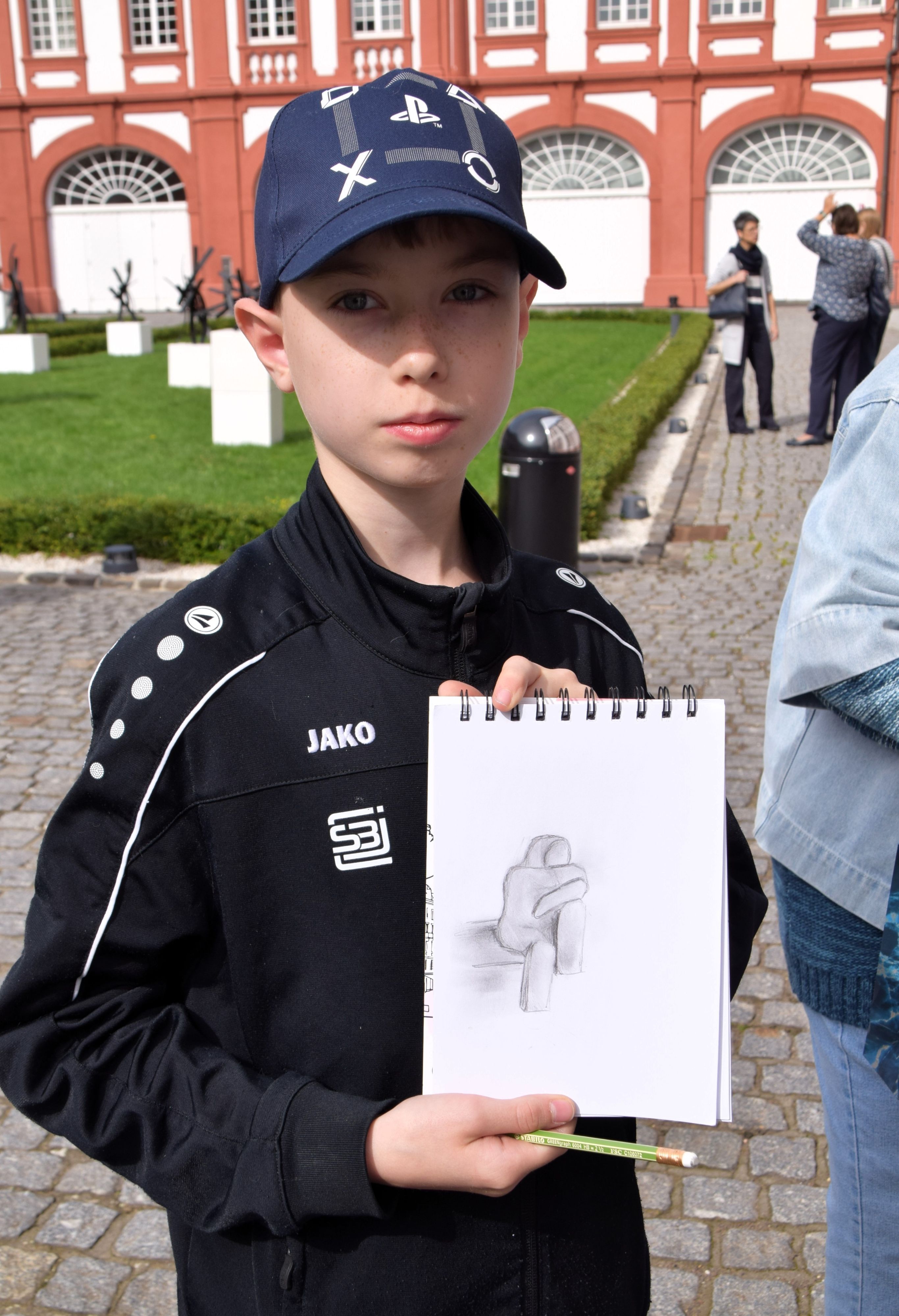 Auf dem Bild ist ein Junge mit einer Zeichnung zu sehen.