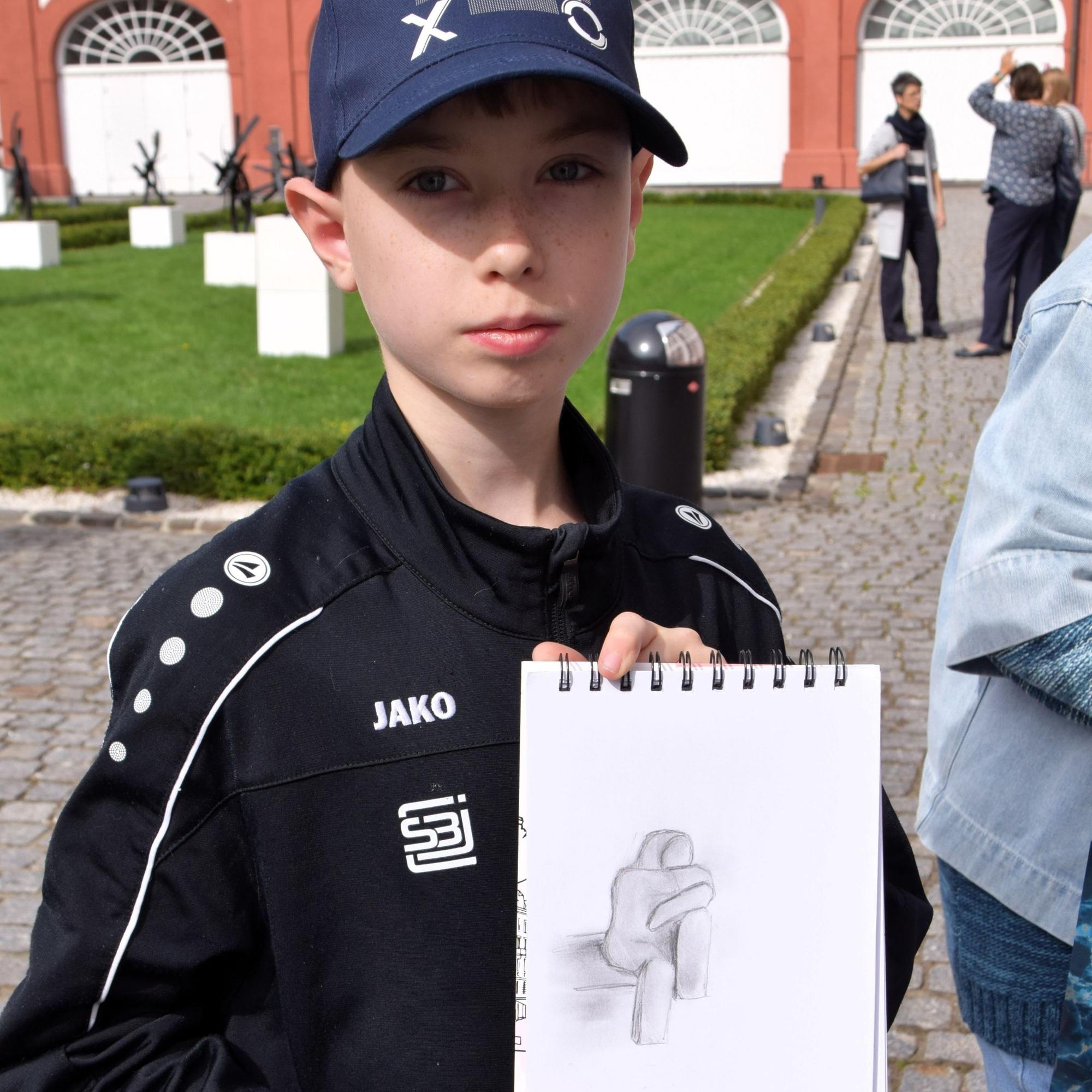 Auf dem Bild ist ein Junge mit einer Zeichnung zu sehen.