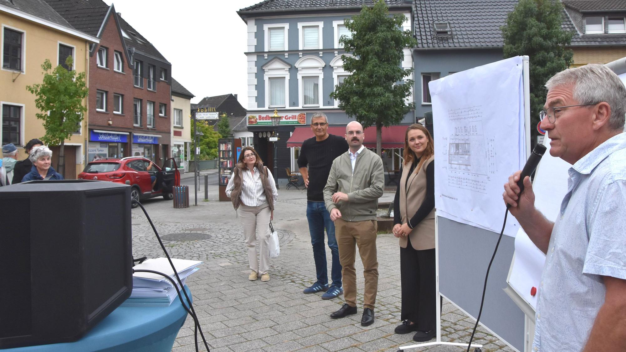 Auf dem Bild ist eine Gruppe von Menschen auf dem Marktplatz zu sehen.