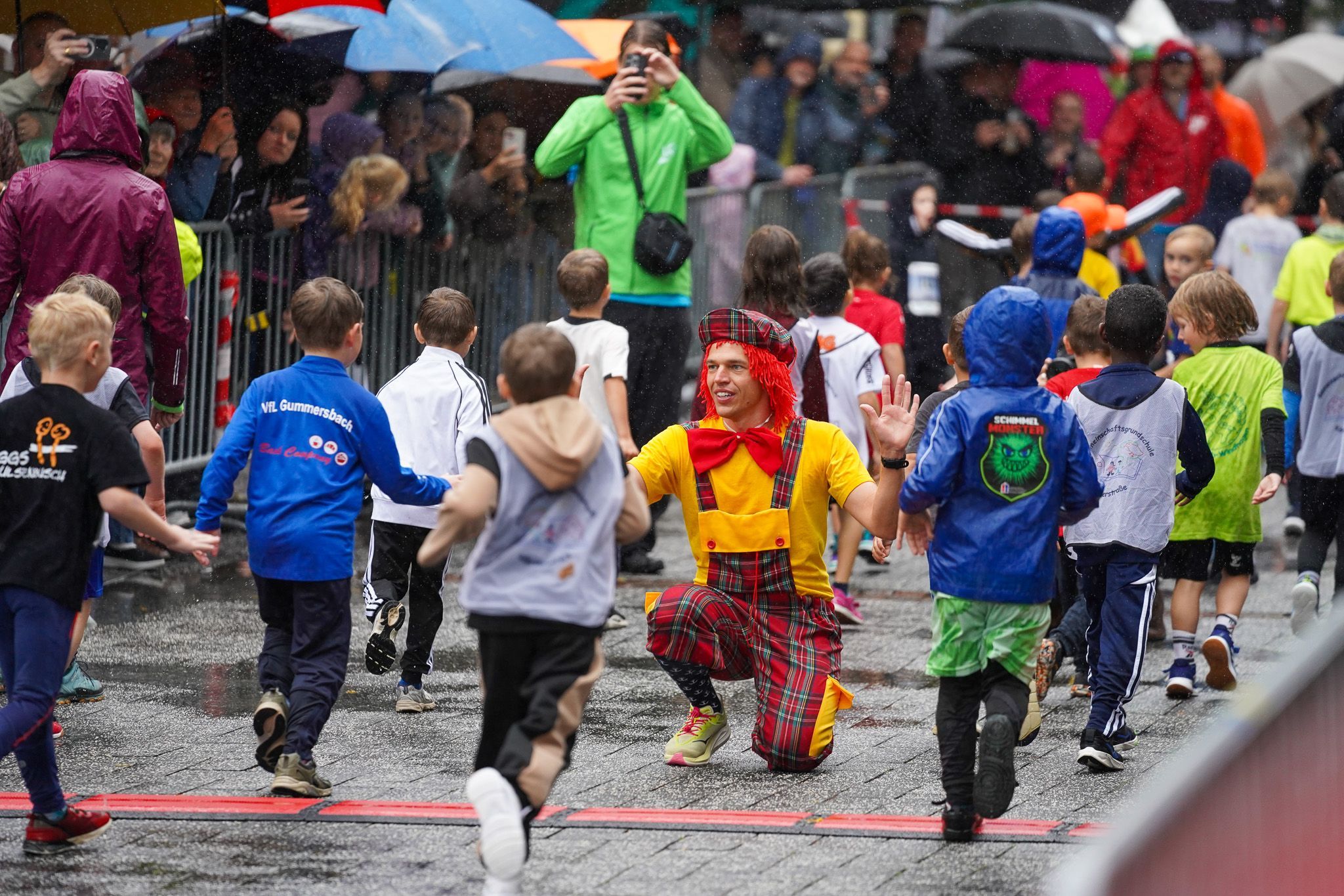 Der Laufclown kniet im Ziel und klatscht die Kinder ab.