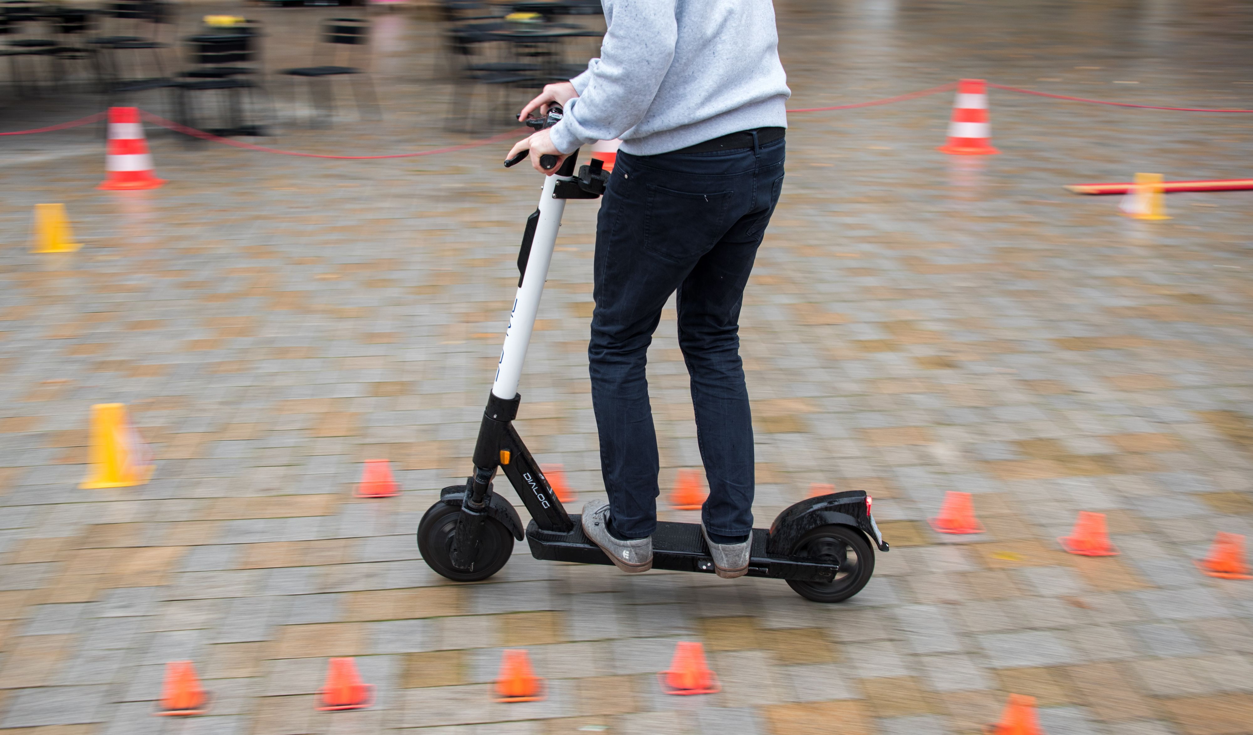 Ein Mitarbeiter eines Anbieters für E-Scooter fährt während eines Fahrsicherheitstrainings durch einen Hindernisparcours.