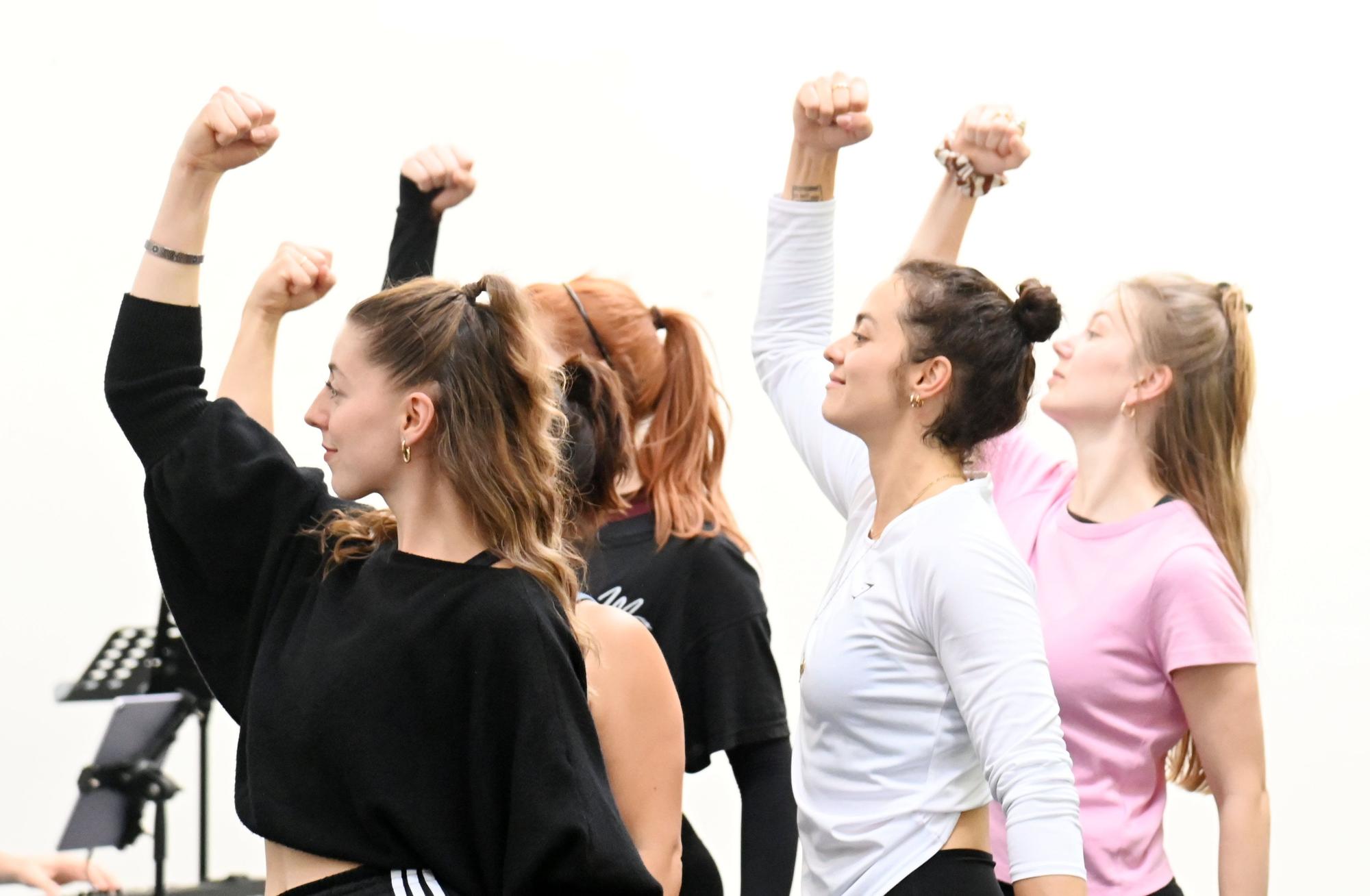 Die Mitwirkenden proben seit zwei Wochen für das neue Musical „Kick Like a Woman.“ Fünf Frauen stehen mit erhobenen Fäusten im Proberaum.