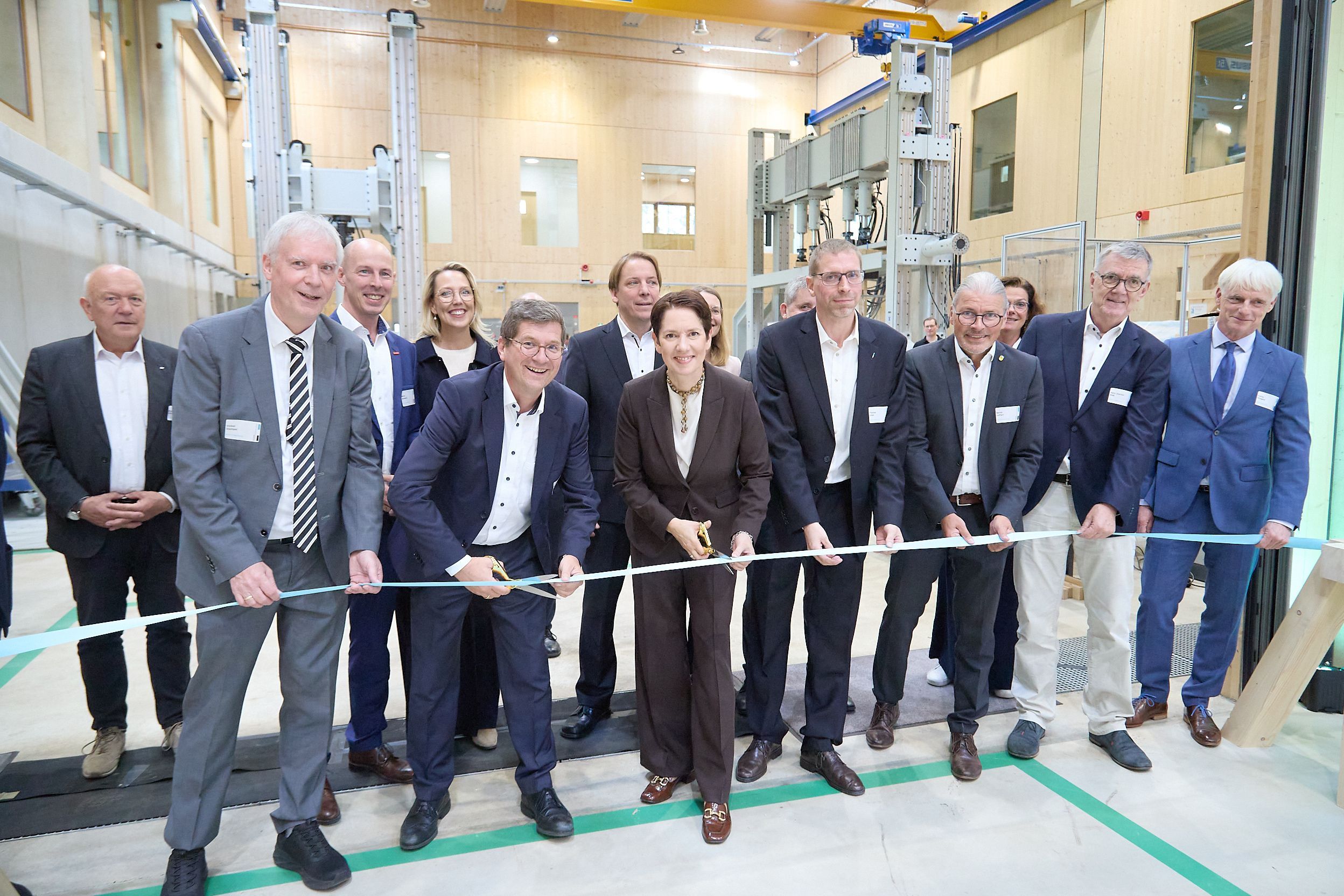 Zahlreiche Personen haben sich um Ministerin Silke Gorißen (vorne, Mitte) versammelt, die das symbolische Band zur Eröffnung durchschneidet.