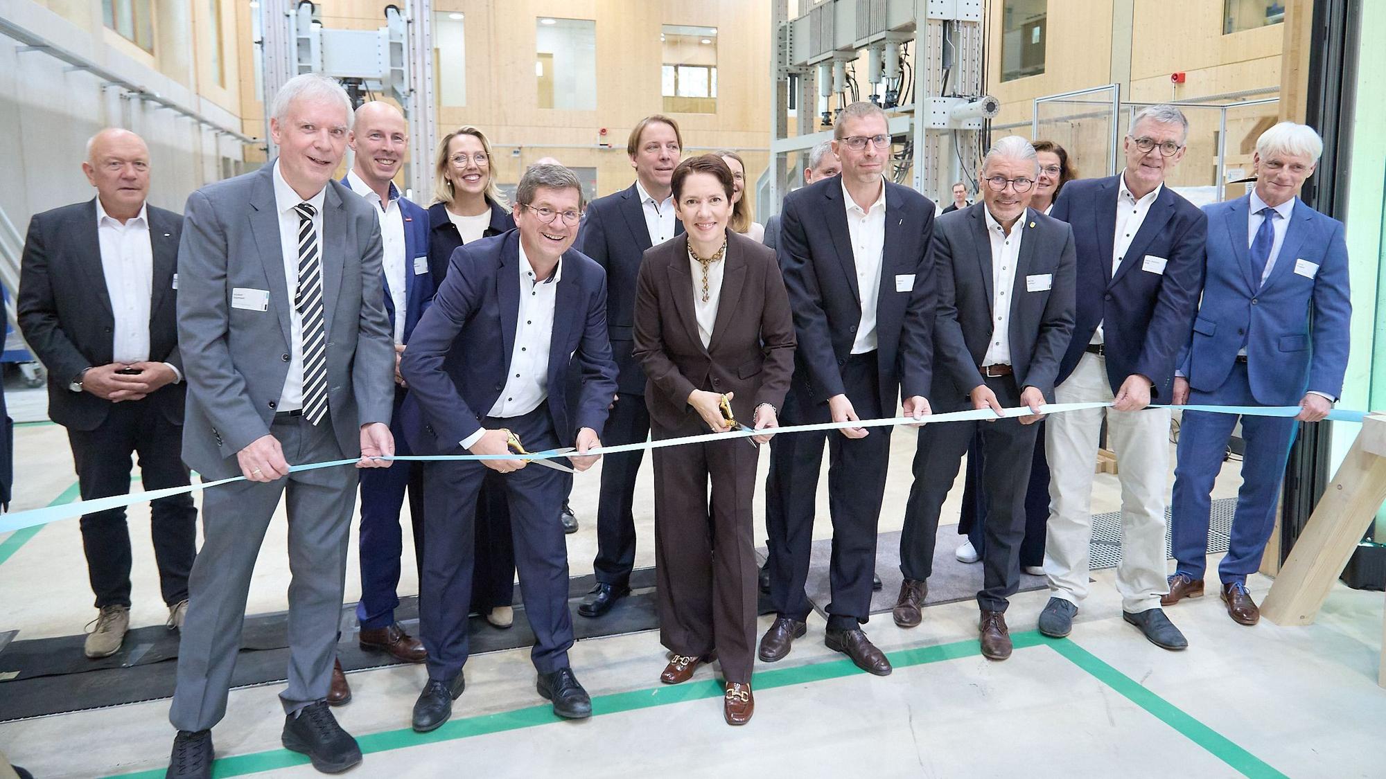 Zahlreiche Personen haben sich um Ministerin Silke Gorißen (vorne, Mitte) versammelt, die das symbolische Band zur Eröffnung durchschneidet.