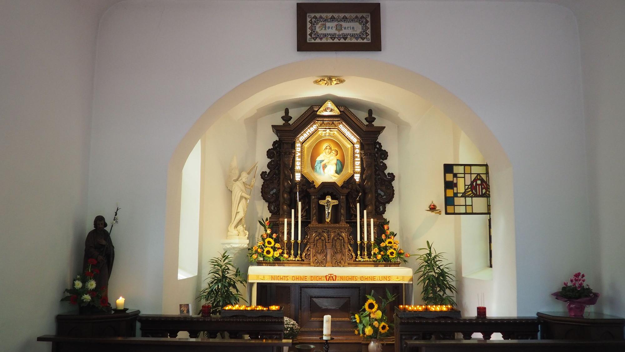Vor dem Altar in der Kapelle brennen Kerzen.
