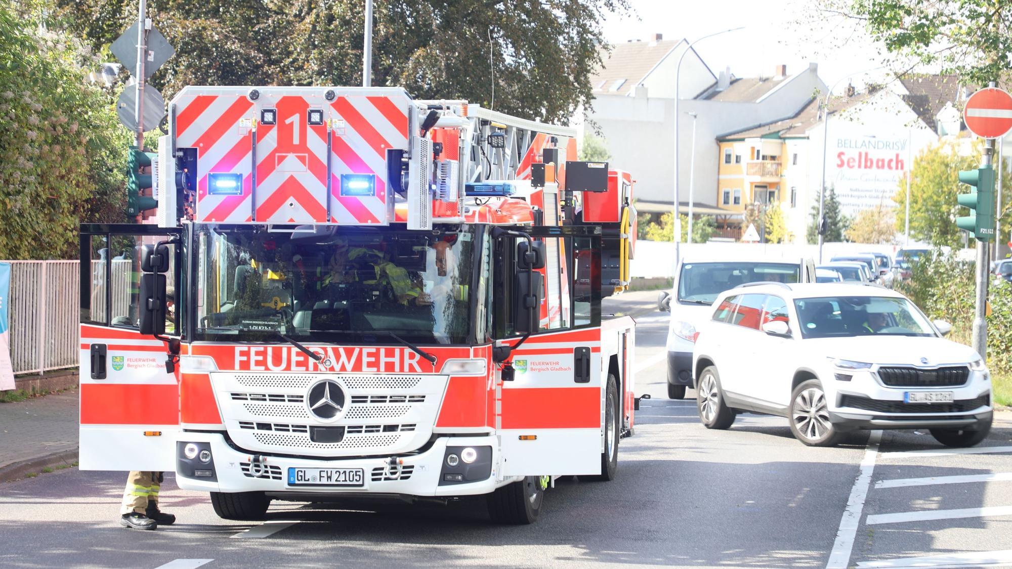 Eine Drehleiter der Feuerwehr steht auf der Straße, Autos wenden davor.