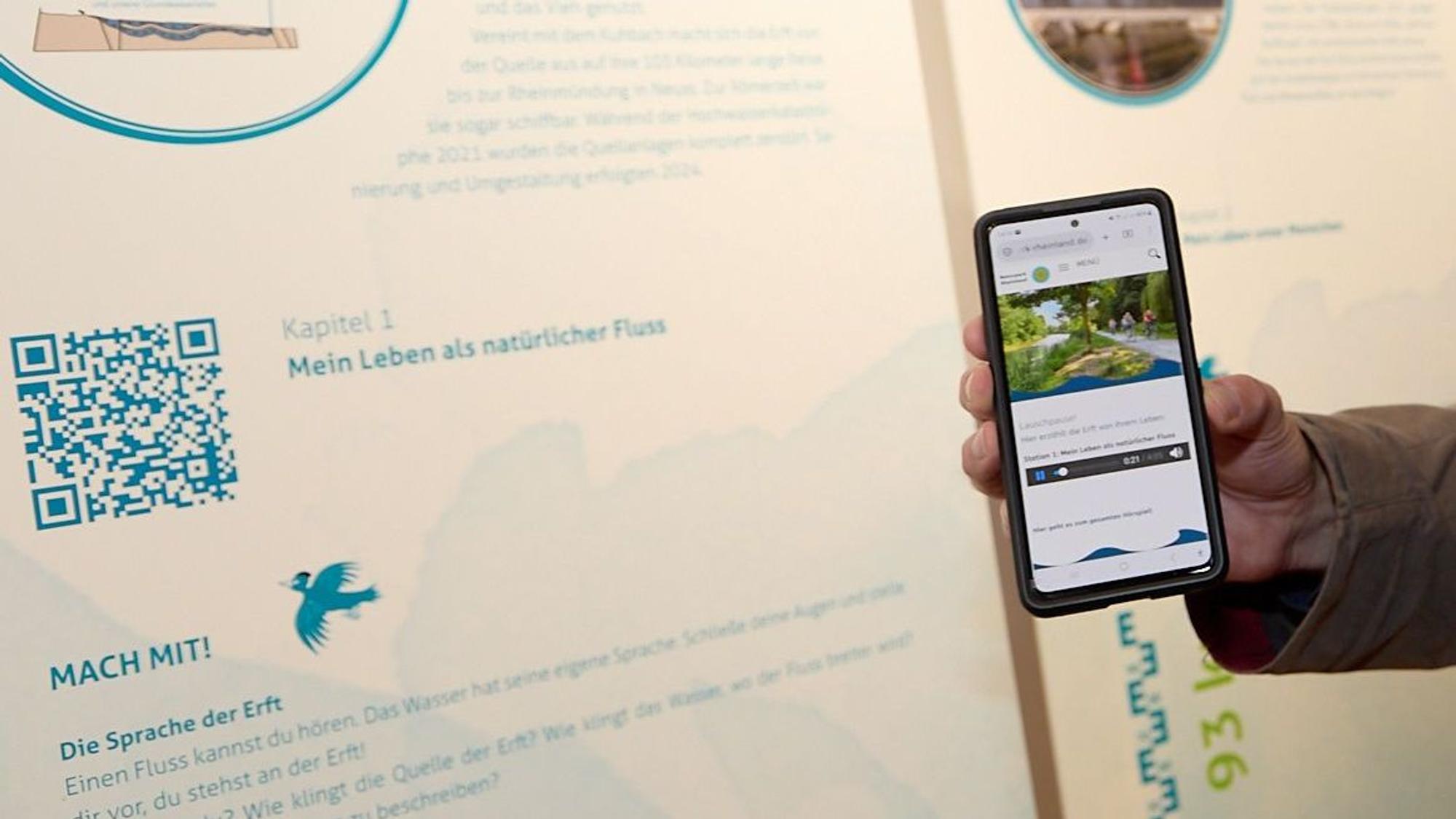 Ein Smartphone wird in die Nähe eines QR-Codes gehalten, um die dazugehörenden Inhalte abzurufen.