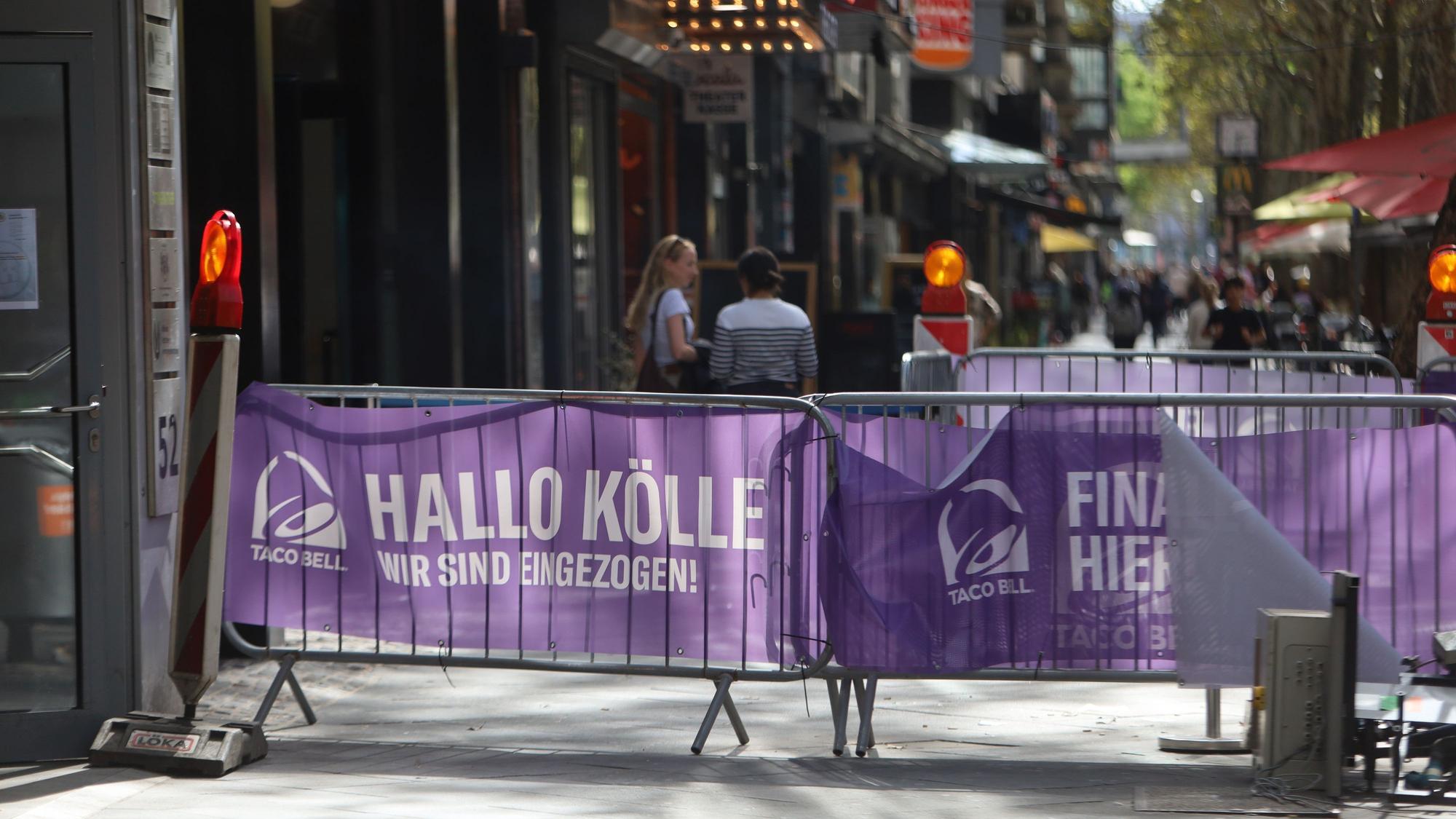 Auf Absperrgittern vor der neuen Filiale von Taco Bell in Köln steht: „Hallo Kölle, Finally Here“