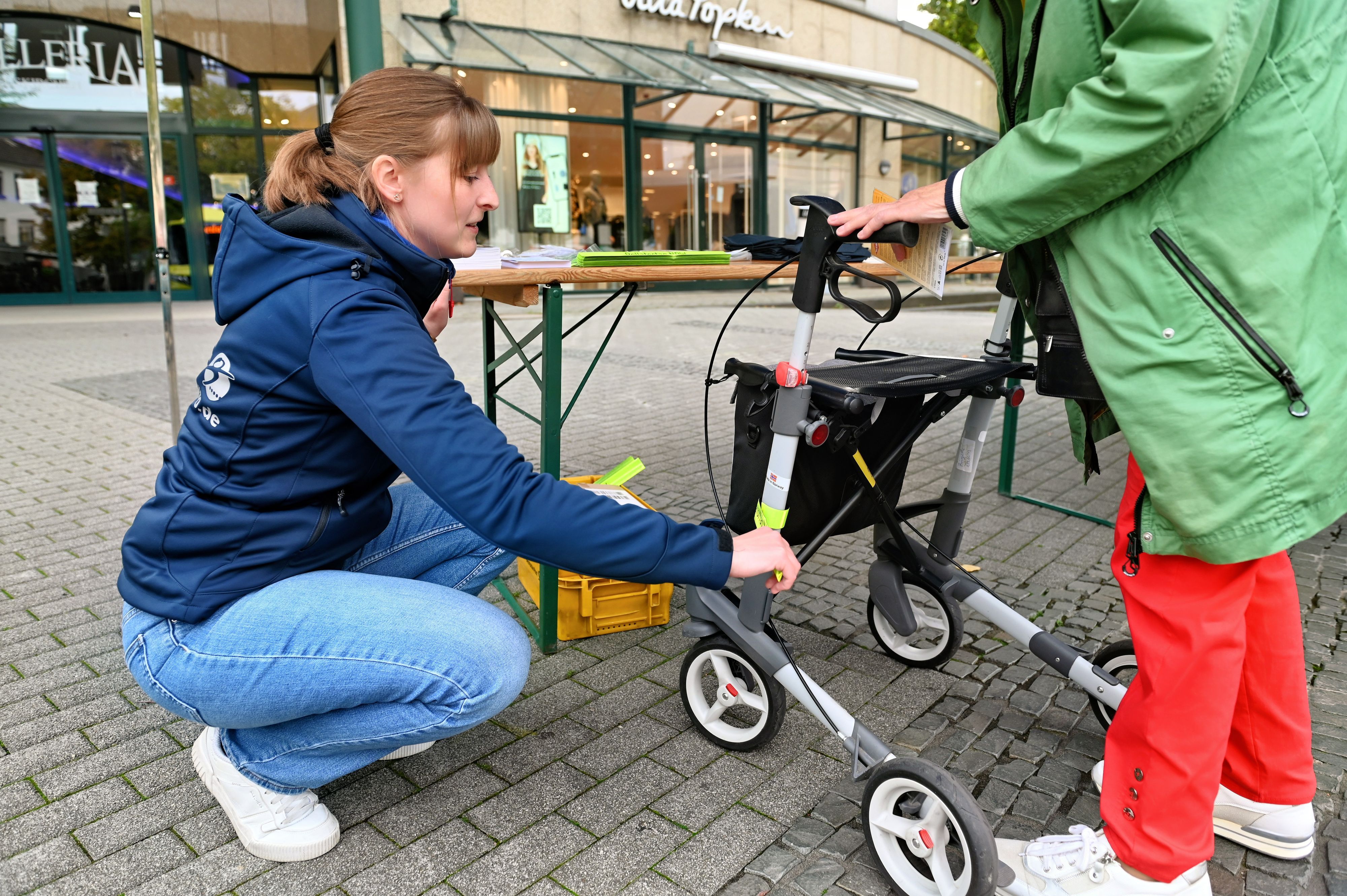 Eine Frau klebt einen Reflektor an einen Rollator.