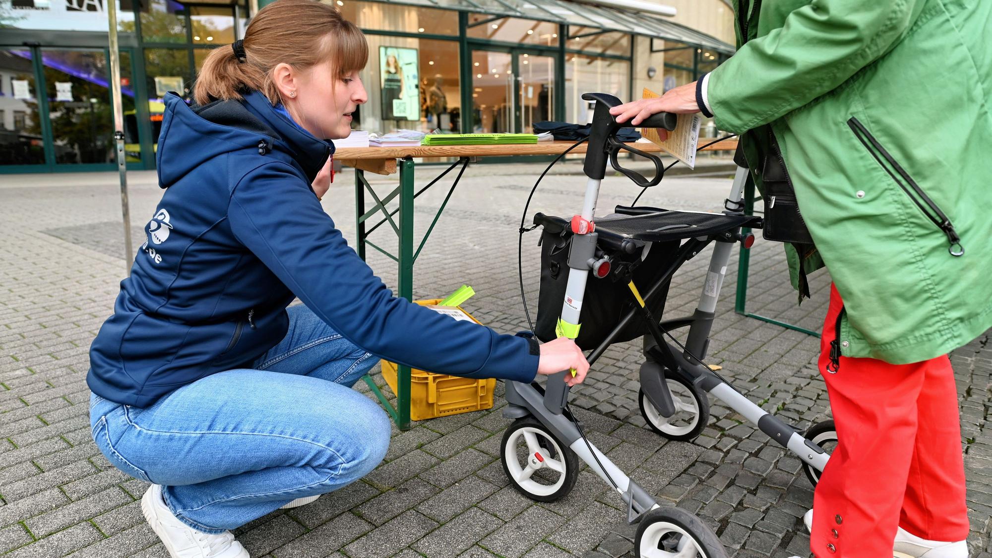 Eine Frau klebt einen Reflektor an einen Rollator.