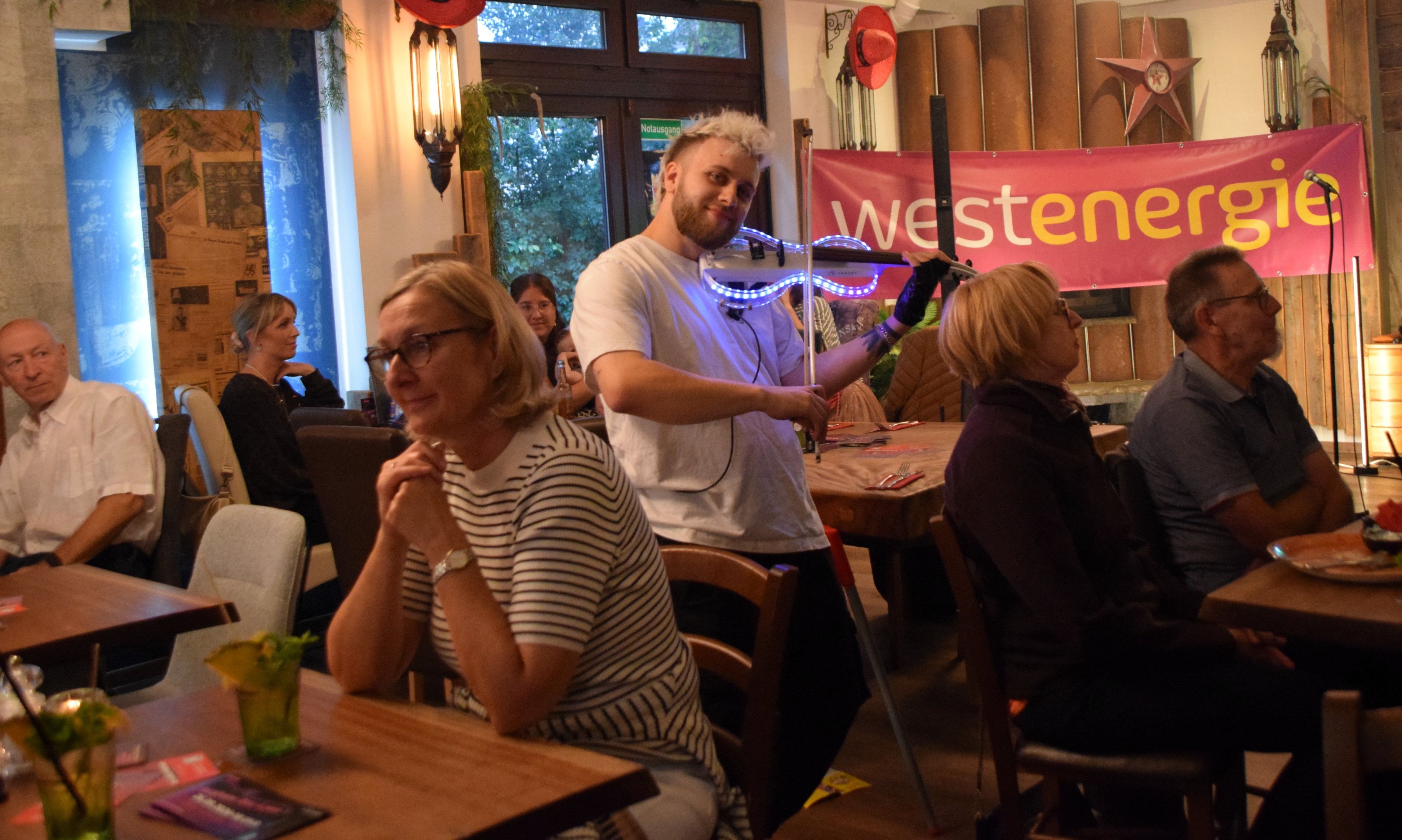Ein Mann spielt auf einer gläsernen und beleuchteten Geige.