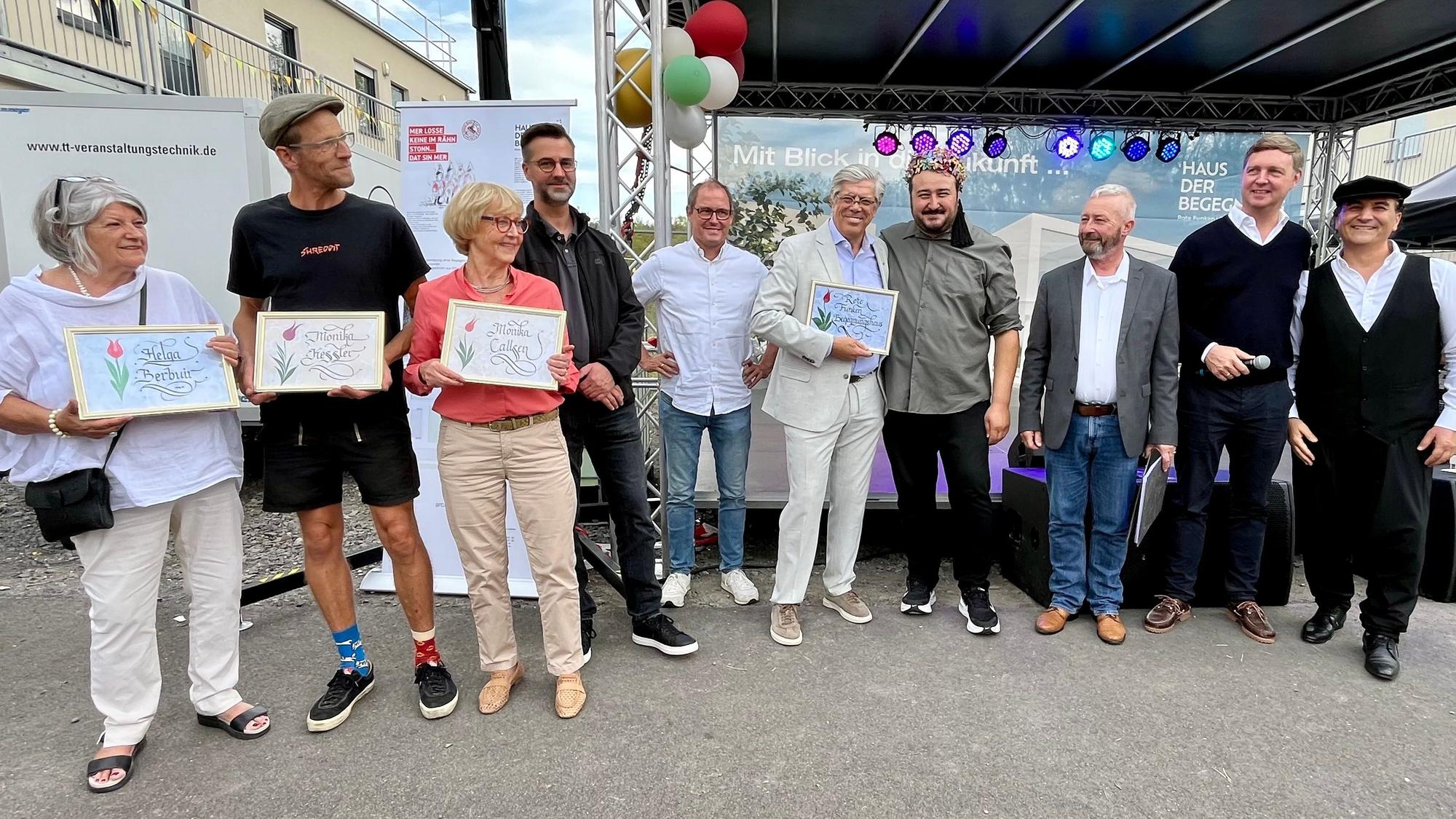 Das Bild zeigt Personen von der Flüchtlingshilfe, der Kirchengemeinden, der Stadt Erftstadt sowie der Roten Funken auf der Bühne.