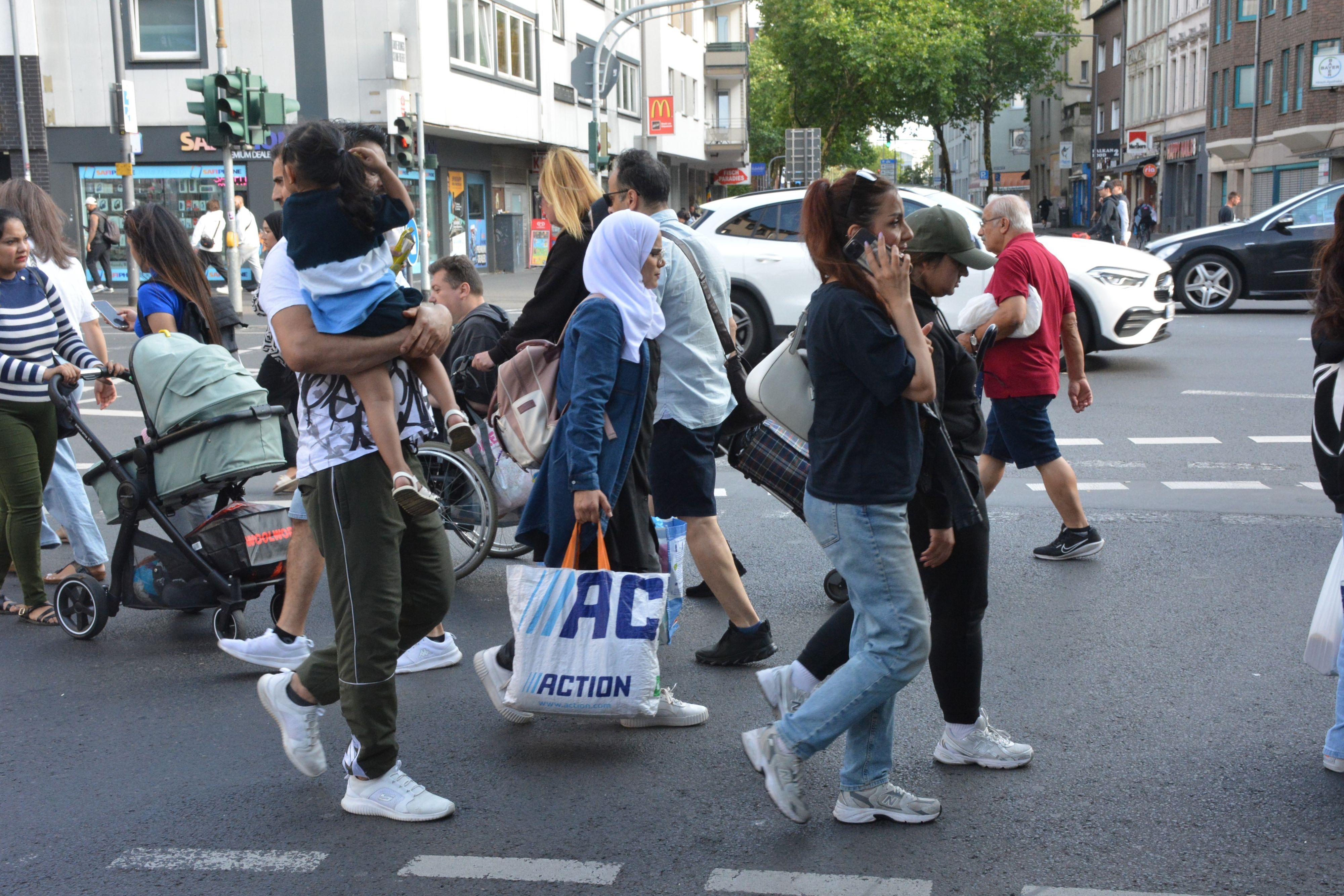 Zahlreiche Menschen überqueren bei Grün eine Straße.