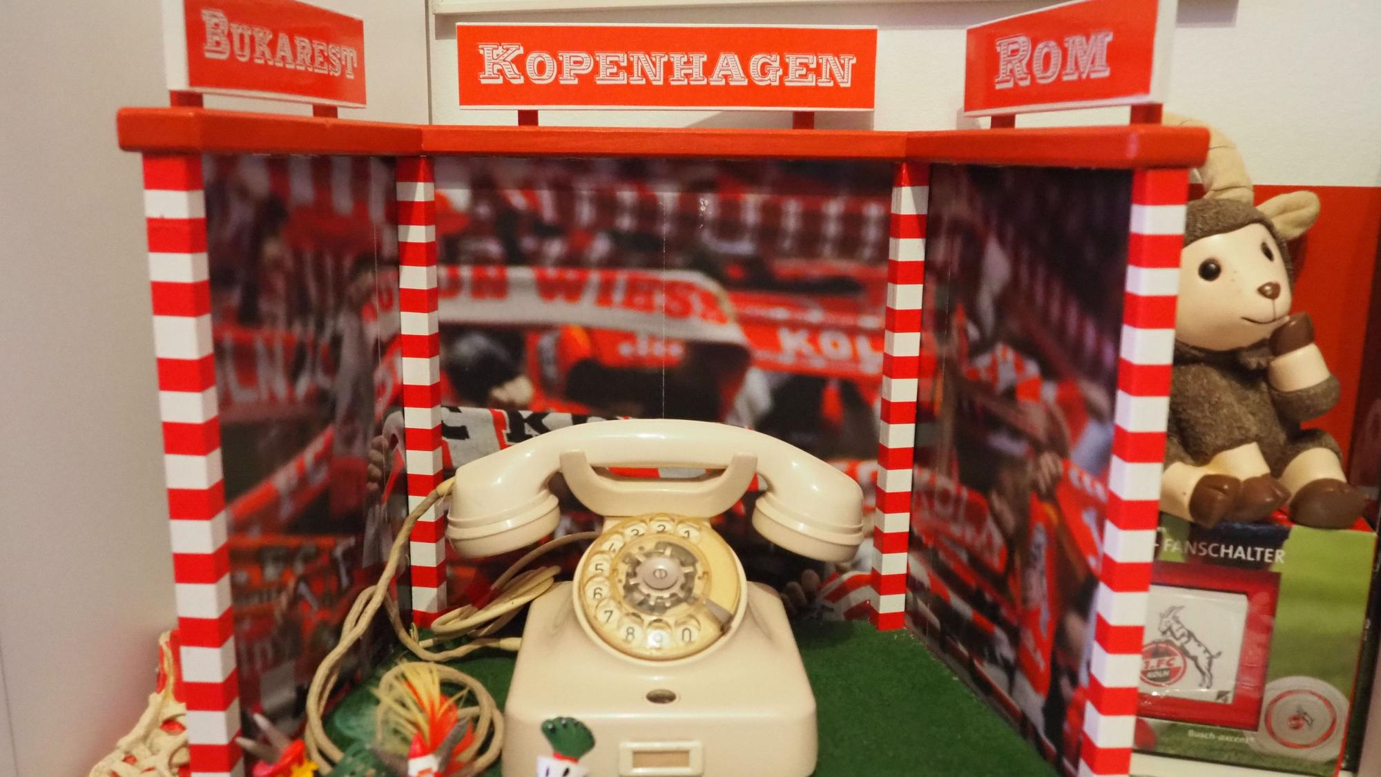 Ein Wählscheibentelefon steht zwischen rotweißen Pfosten.