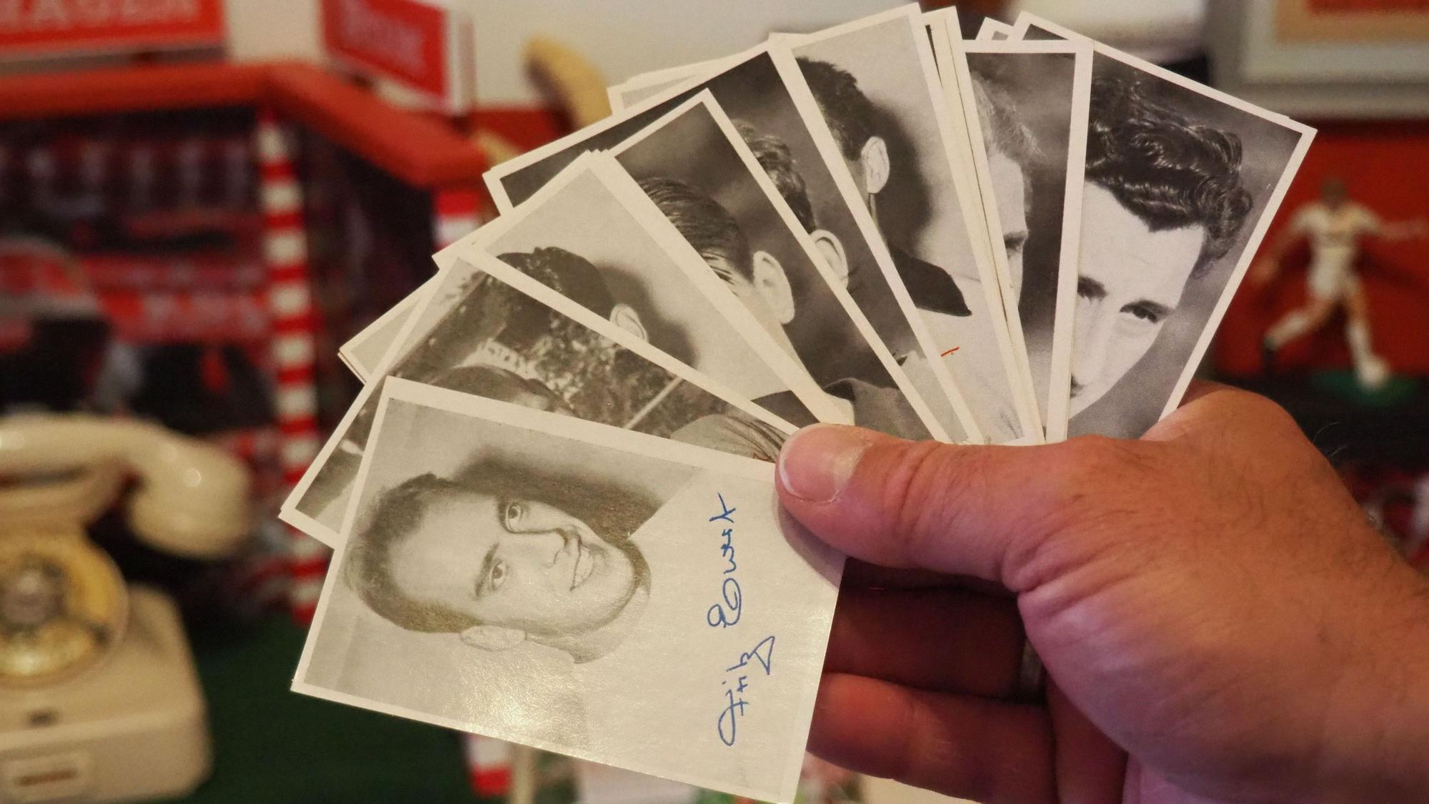 Eine Hand hält Autogrammkarten in Schwarz-Weiß, aufgefächert wie ein Kartenspiel.