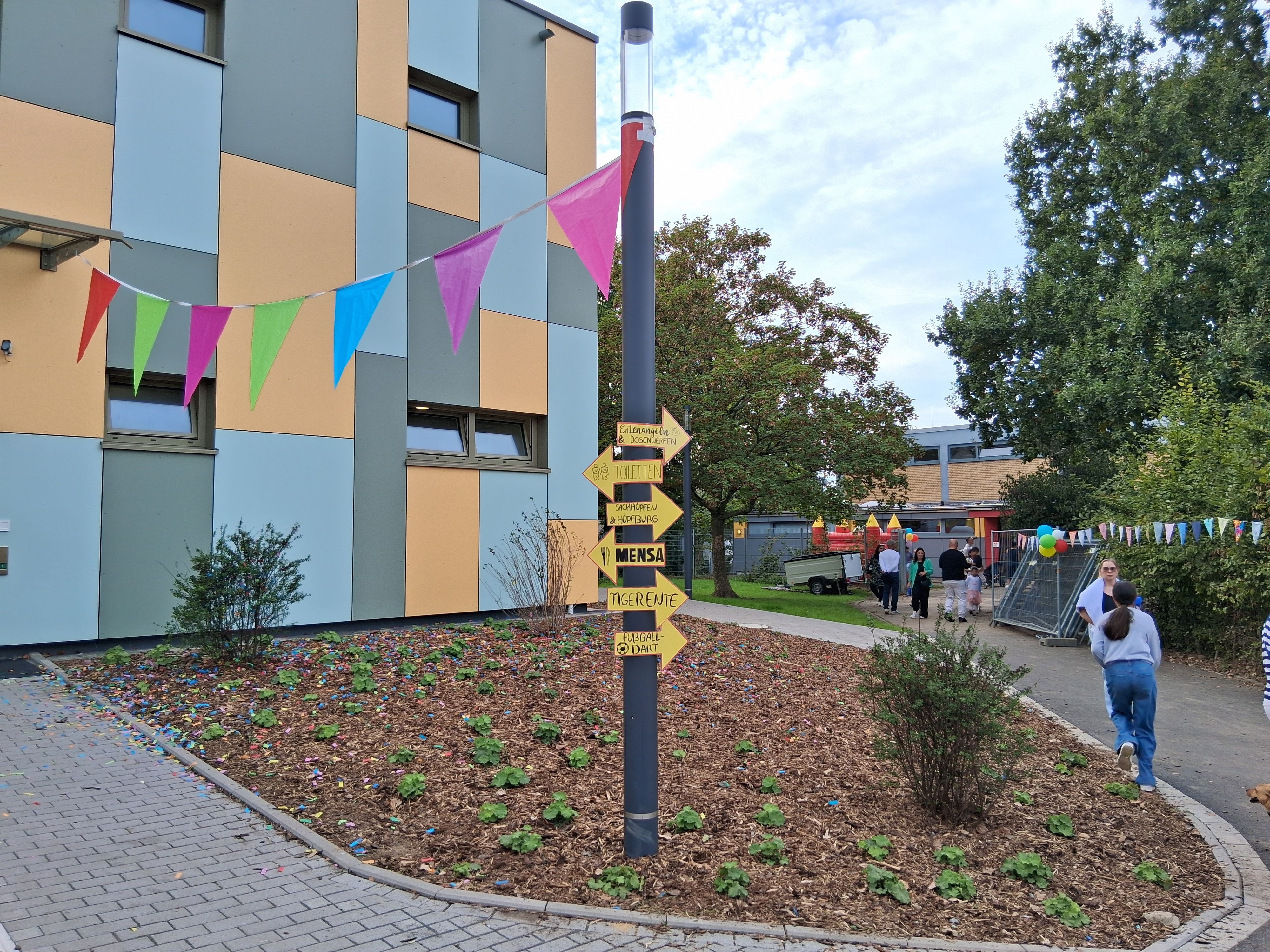 Vor einem Schulgebäude hängen bunte Wimpel.