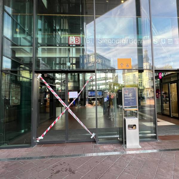 Mittlerweile professionell mit rot-weißem Flatterband als unpassierbar markiert ist eine der beiden elektrischen Schiebetüren zum Haupteingang des ICE-Bahnhofs in Siegburg. Sie ist seit mindestens drei Wochen (Stand 29.9.26) defekt.