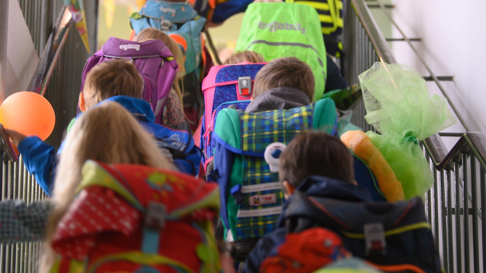 Grundschüler einer ersten Klasse begeben sich durchs Treppenhaus der Schule in ihr Klassenzimmer.