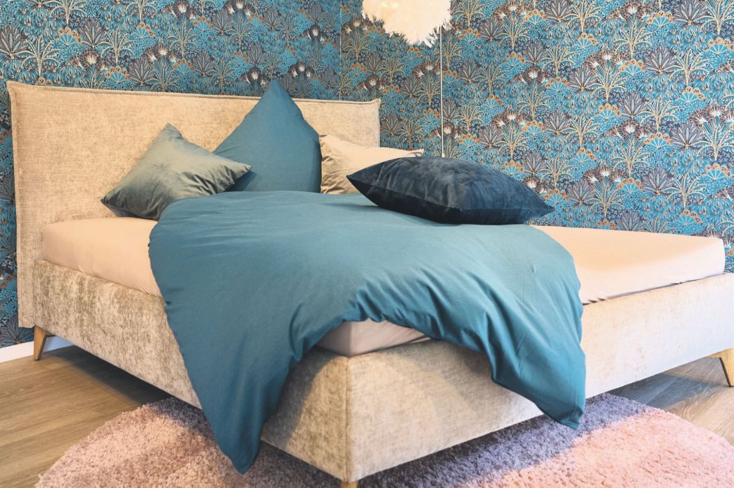 Stilvolles Schlafzimmer mit gepolstertem Boxspringbett und farblich abgestimmten Kissen