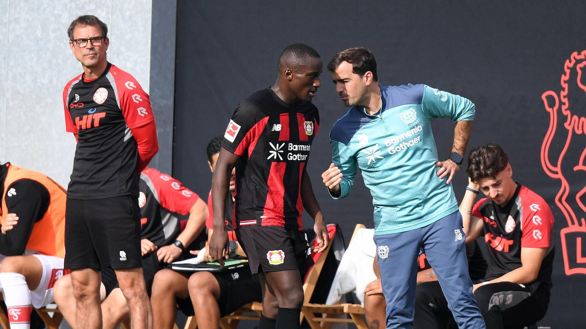 Carles Martínez (r.) gibt Moussa Diaby Anweisungen. Fortuna Kölns Trainer Matthias Mink beobachtet das Spielgeschehen (l.).