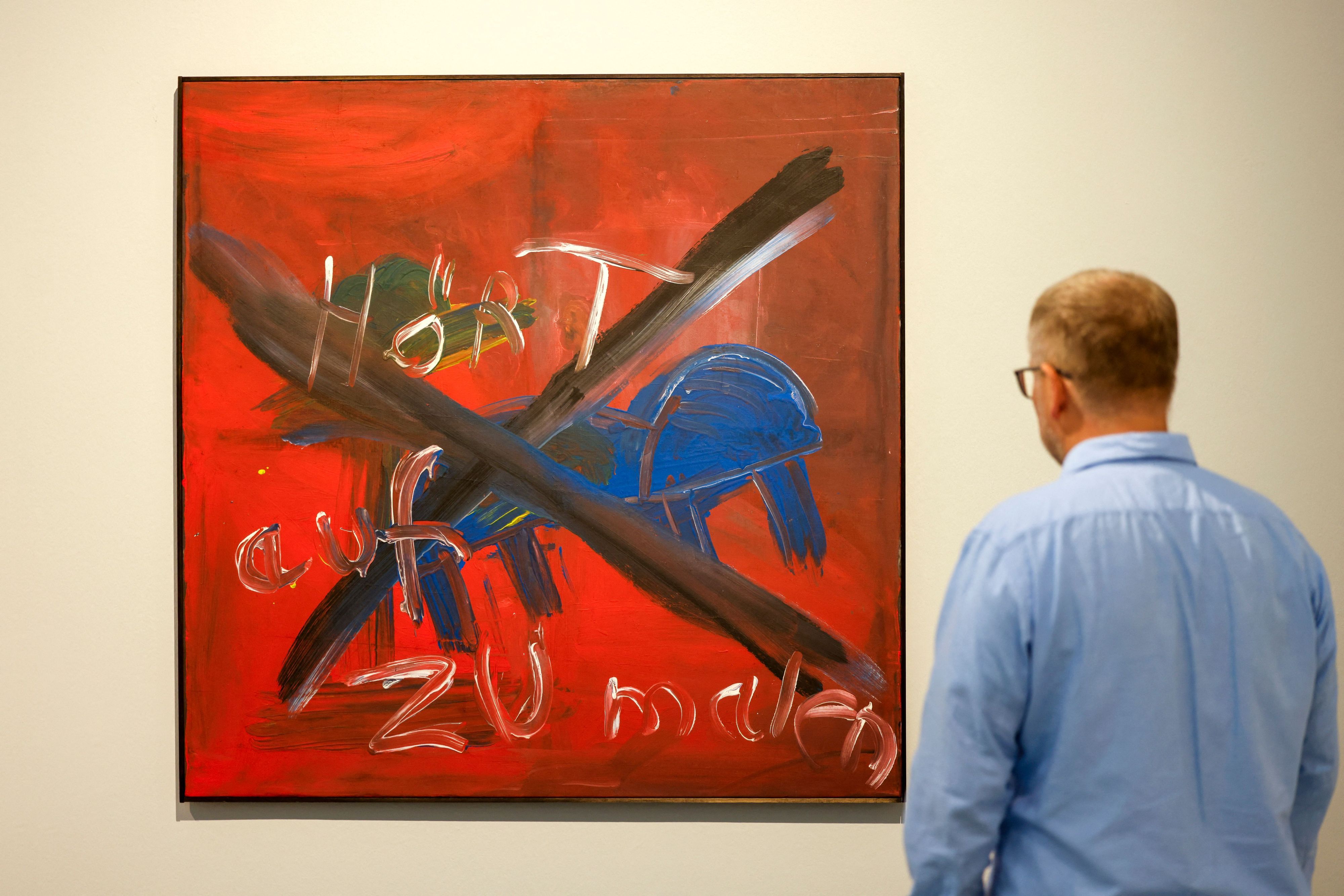 Ein Besucher steht bei einer Vorbesichtigung der Ausstellung "Immendorff" im Kunstpalast vor dem Gemälde "Hört auf zu malen".
