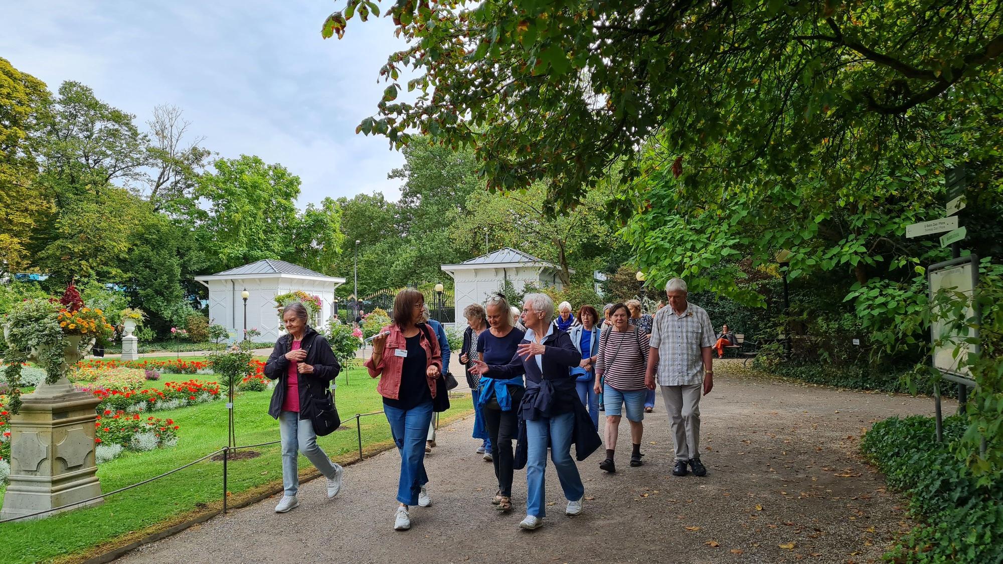 Eine Gruppe von Frauen und Männern geht durch einen Park.