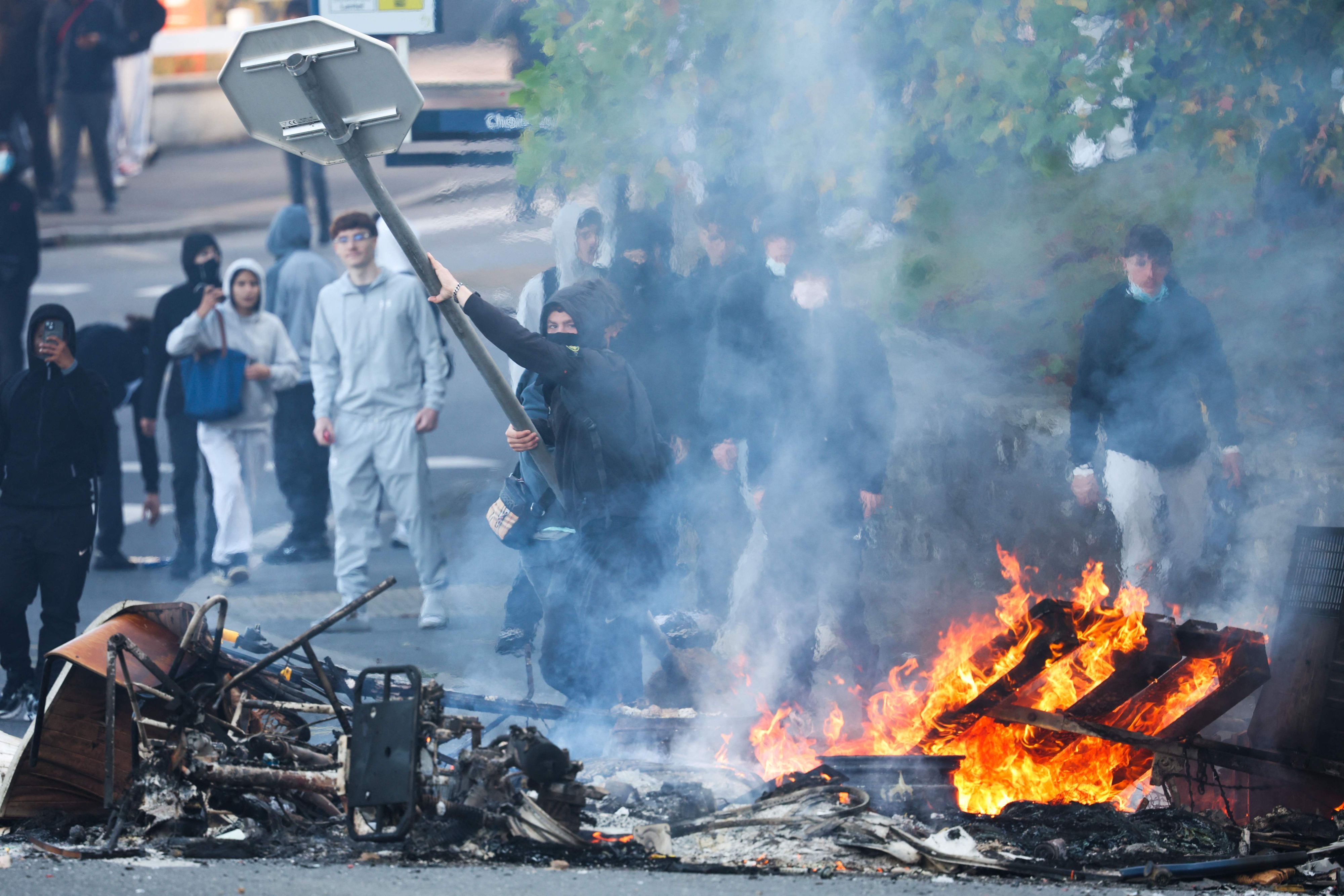 Bei Schülerprotesten in Brest wirft ein Demonstrant ein Stoppschild ins Feuer.