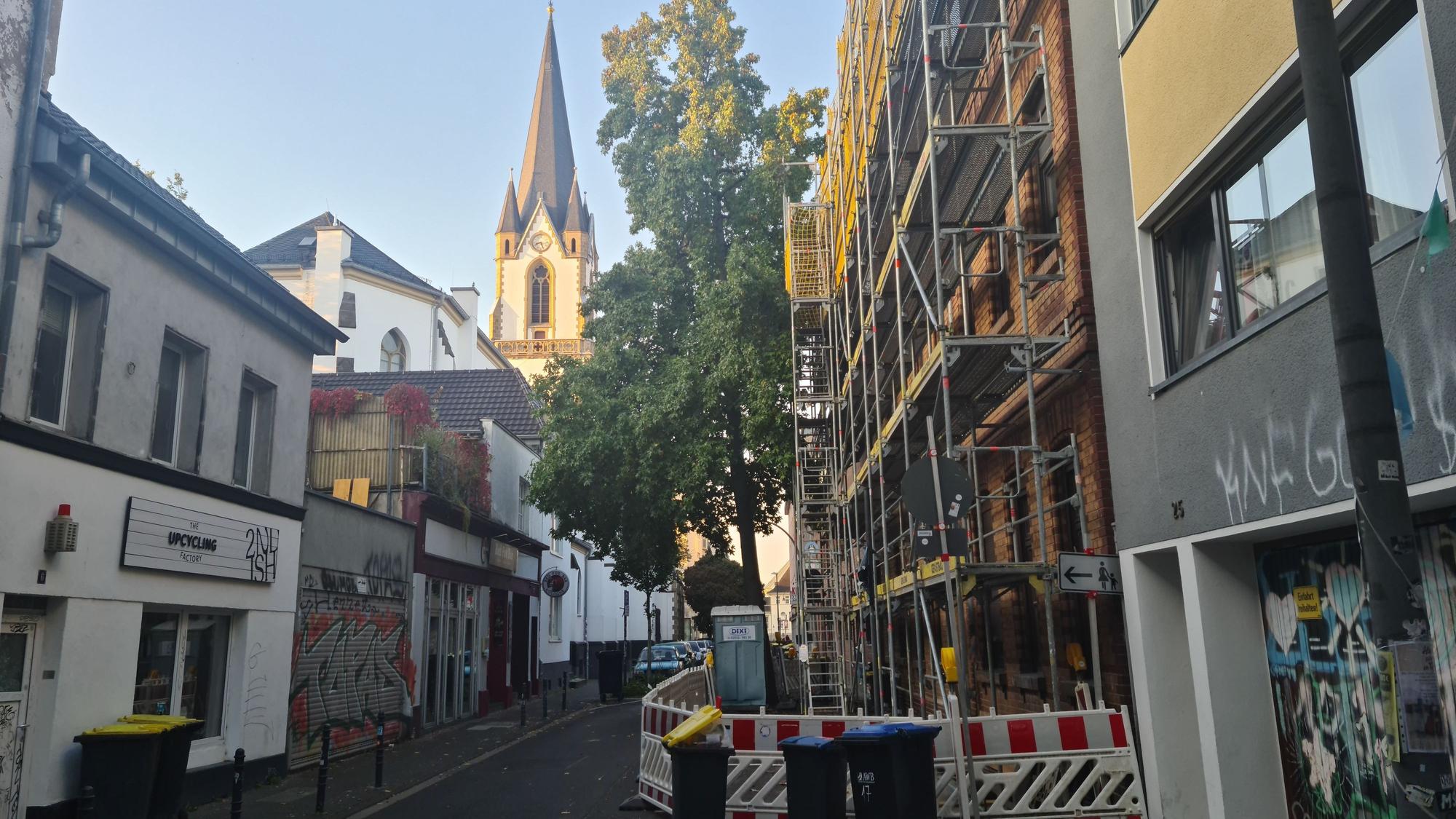 Eine Hausfassade in einer schmalen Straße ist eingerüstet.