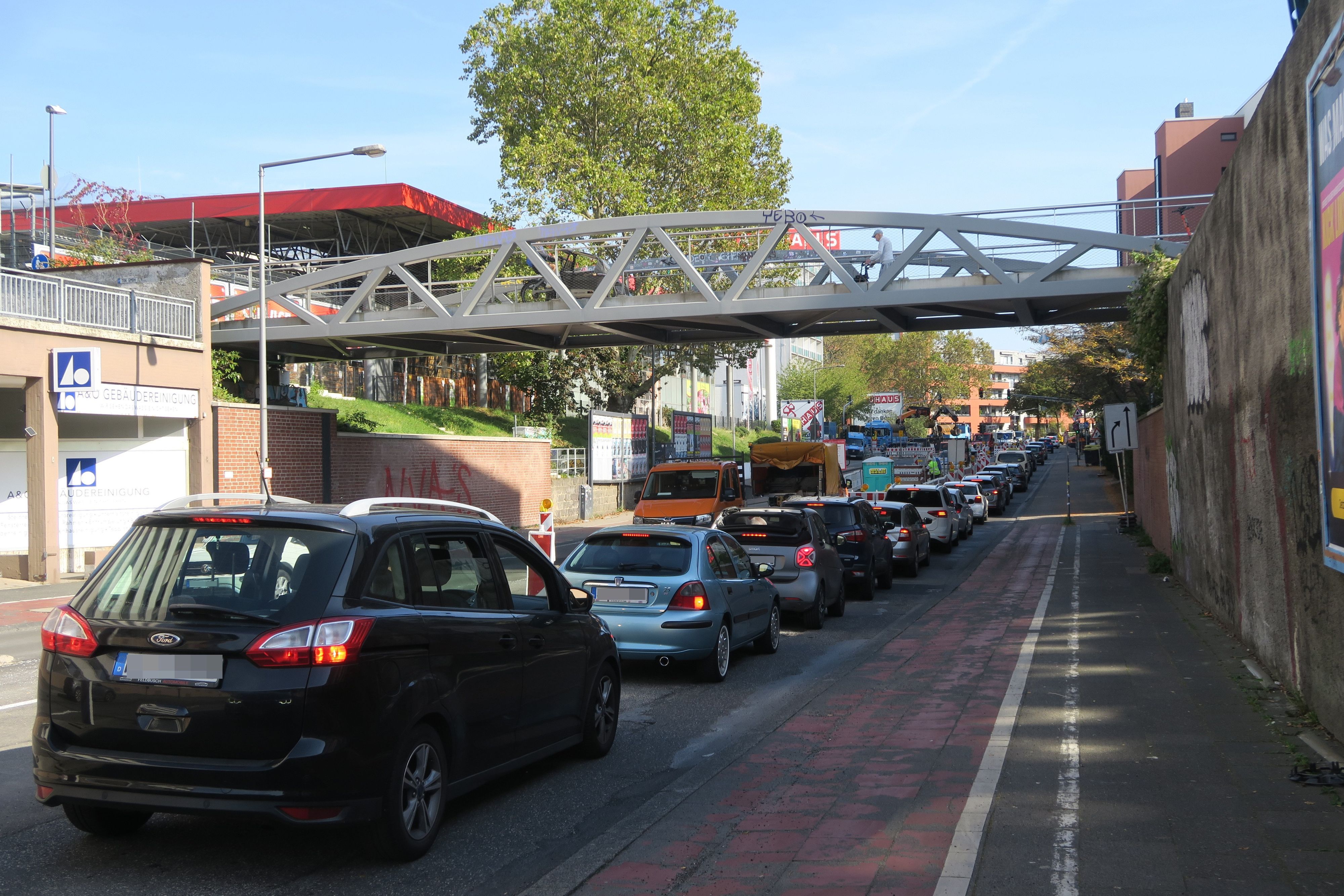 Autos stauen sich an einer Baustelle unter einer Fußgängerbrücke.