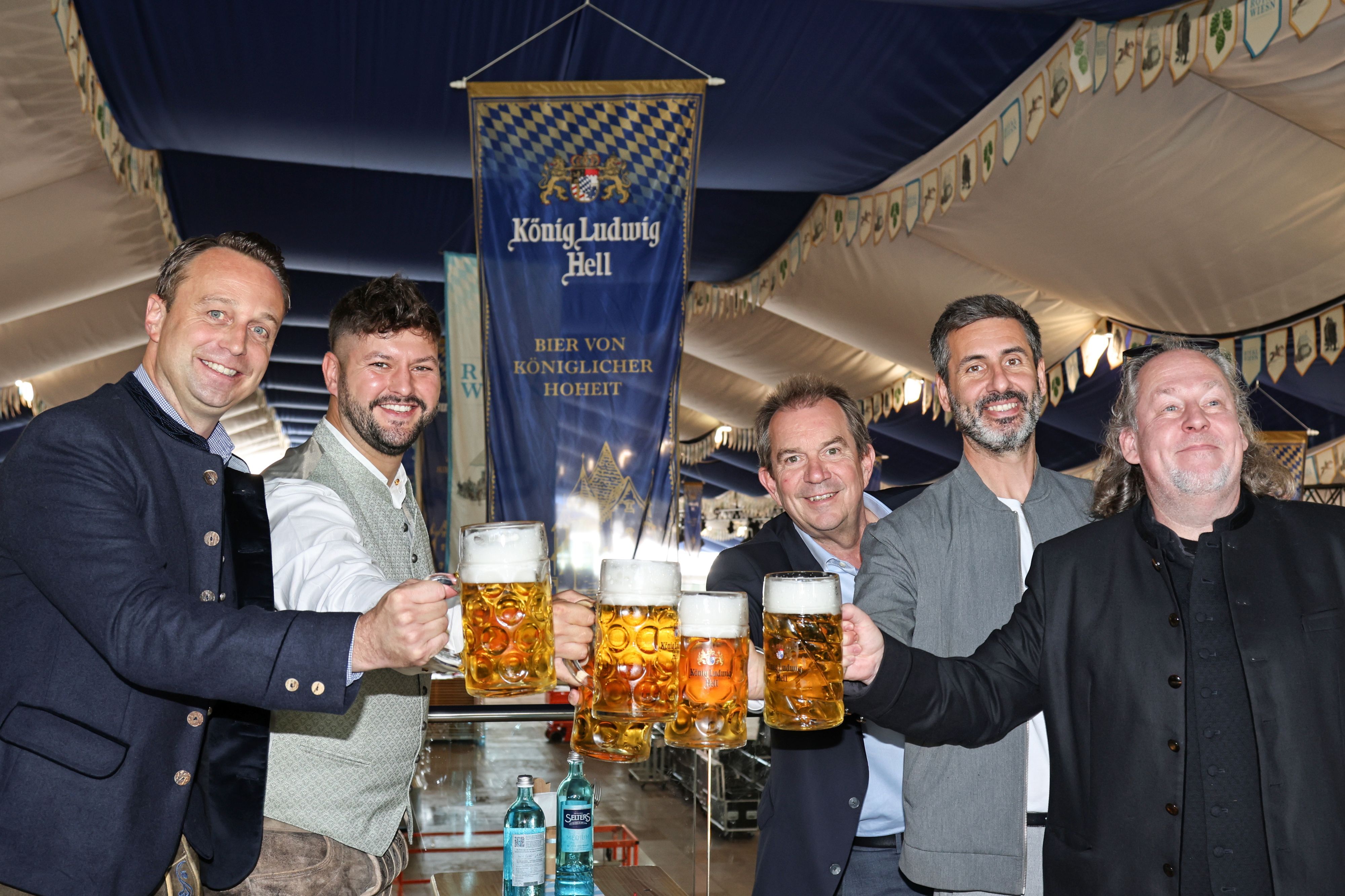 Männer prosten sich mit Bier zu.