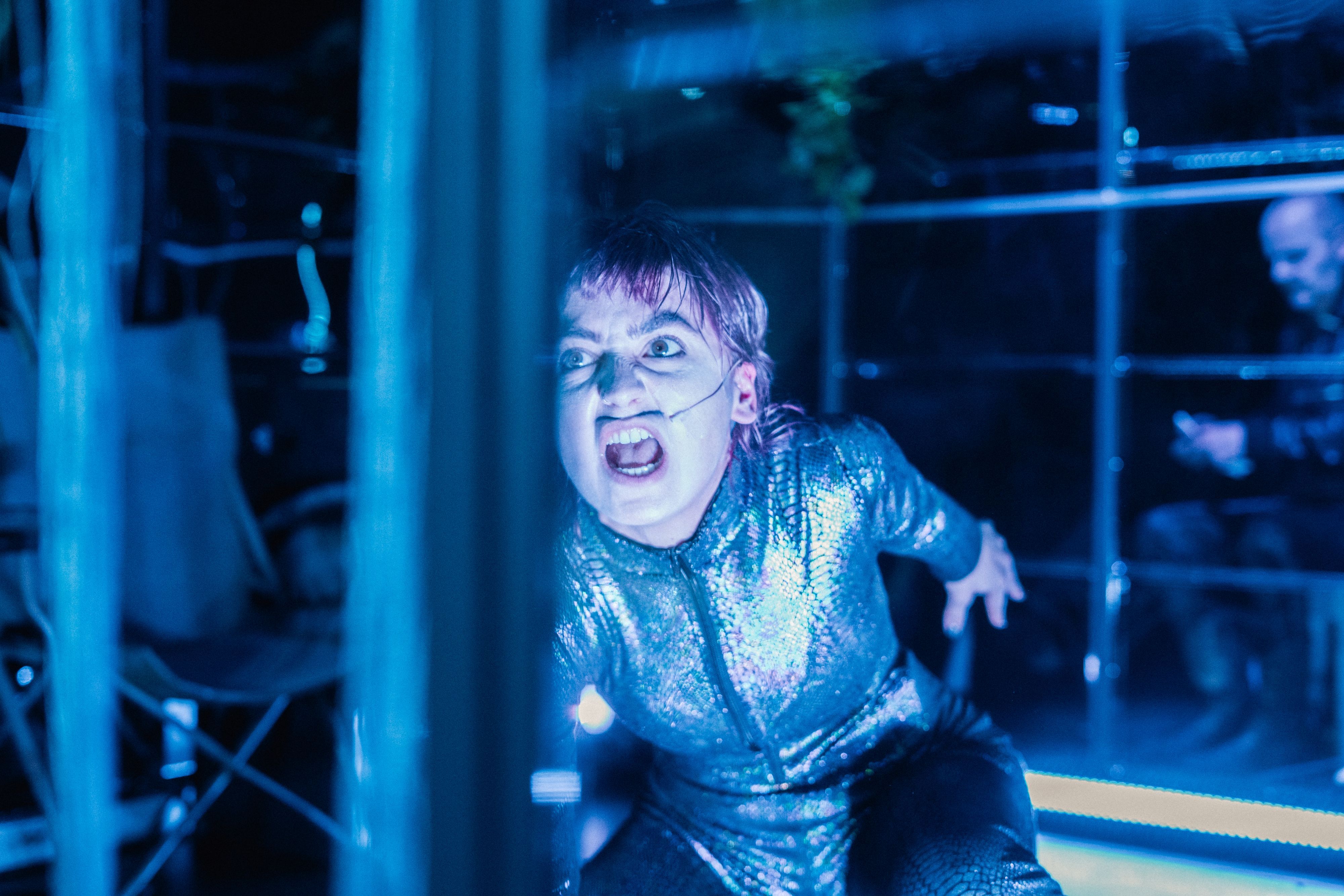 Eine Frau in einem glitzerfarbenen Neopren-Anzug schreit.