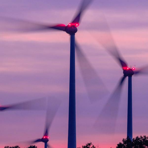 Mit Signallampen beleuchtete Windräder drehen sich nach Sonnenuntergang in einem Windpark.
