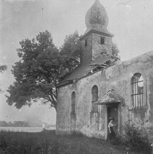 Ein Schwarz-Weiß-Foto zeigt eine kleine Kirche, dahinter ist der Rhein  zu sehen.