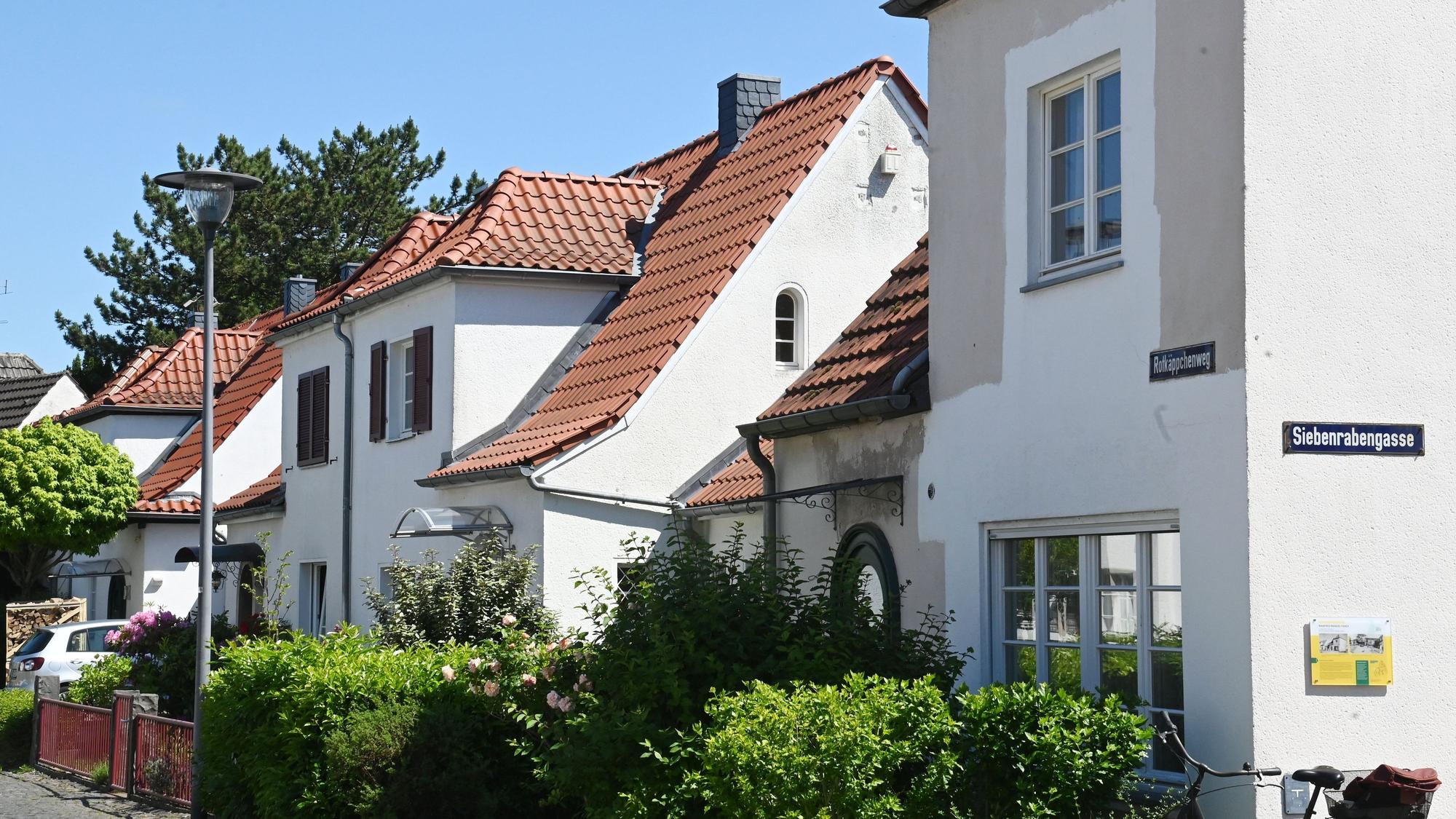 Hübsche weiße Häuser mit orangen Dachziegeln stehen an einer Straße.