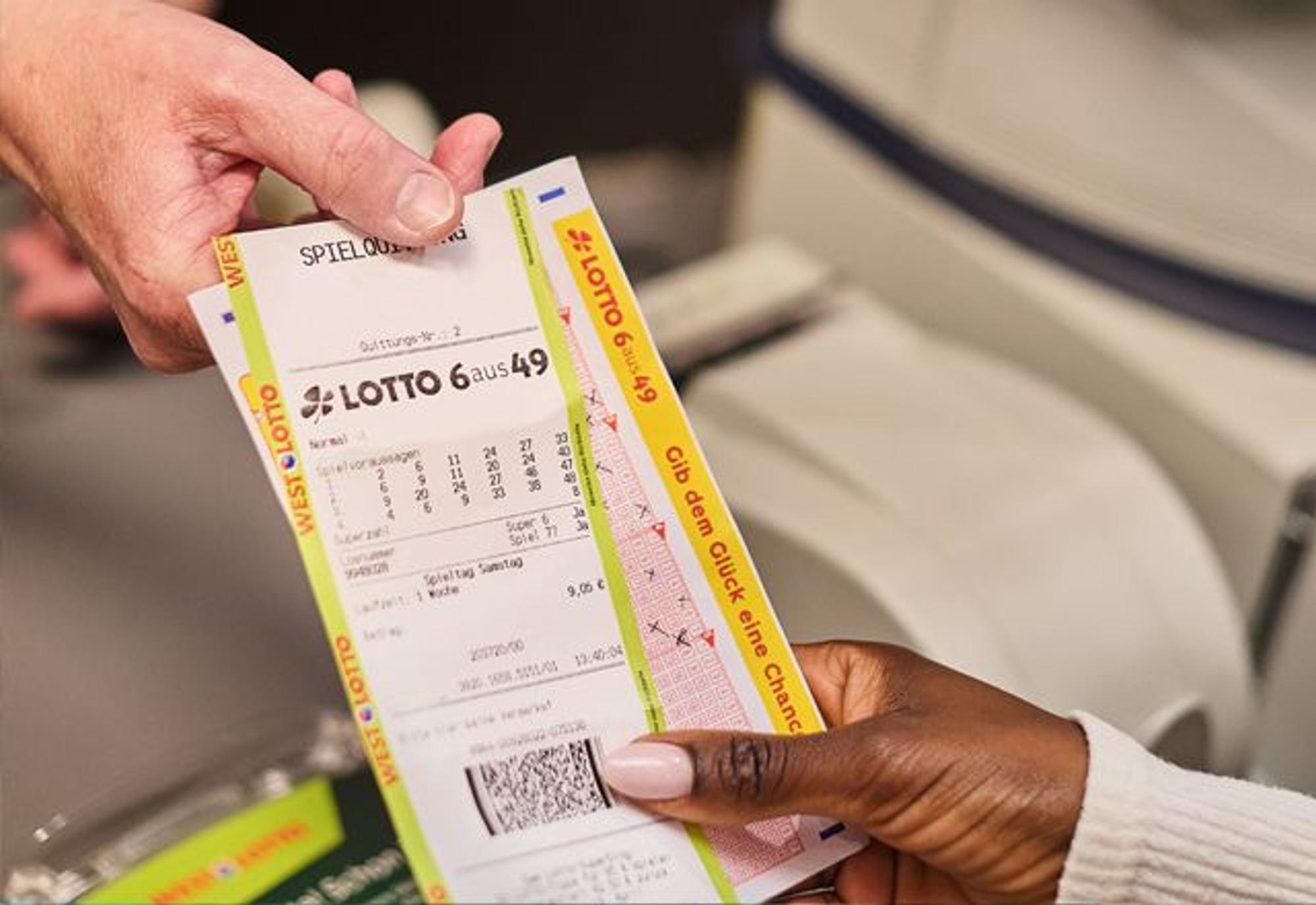 Hand übergibt eine LOTTO-6aus49-Spielquittung an einer Annahmestelle.
