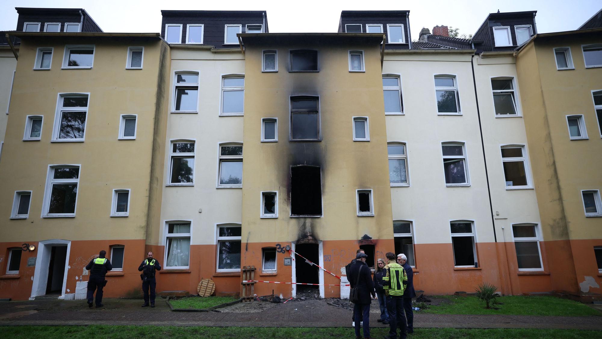 Feuerwehr, Polizei und Brandermittler stehen am Dienstag (13. Oktober) nach einem Brand vor einem Mehrfamilienhaus im Stadtteil Hofstede.