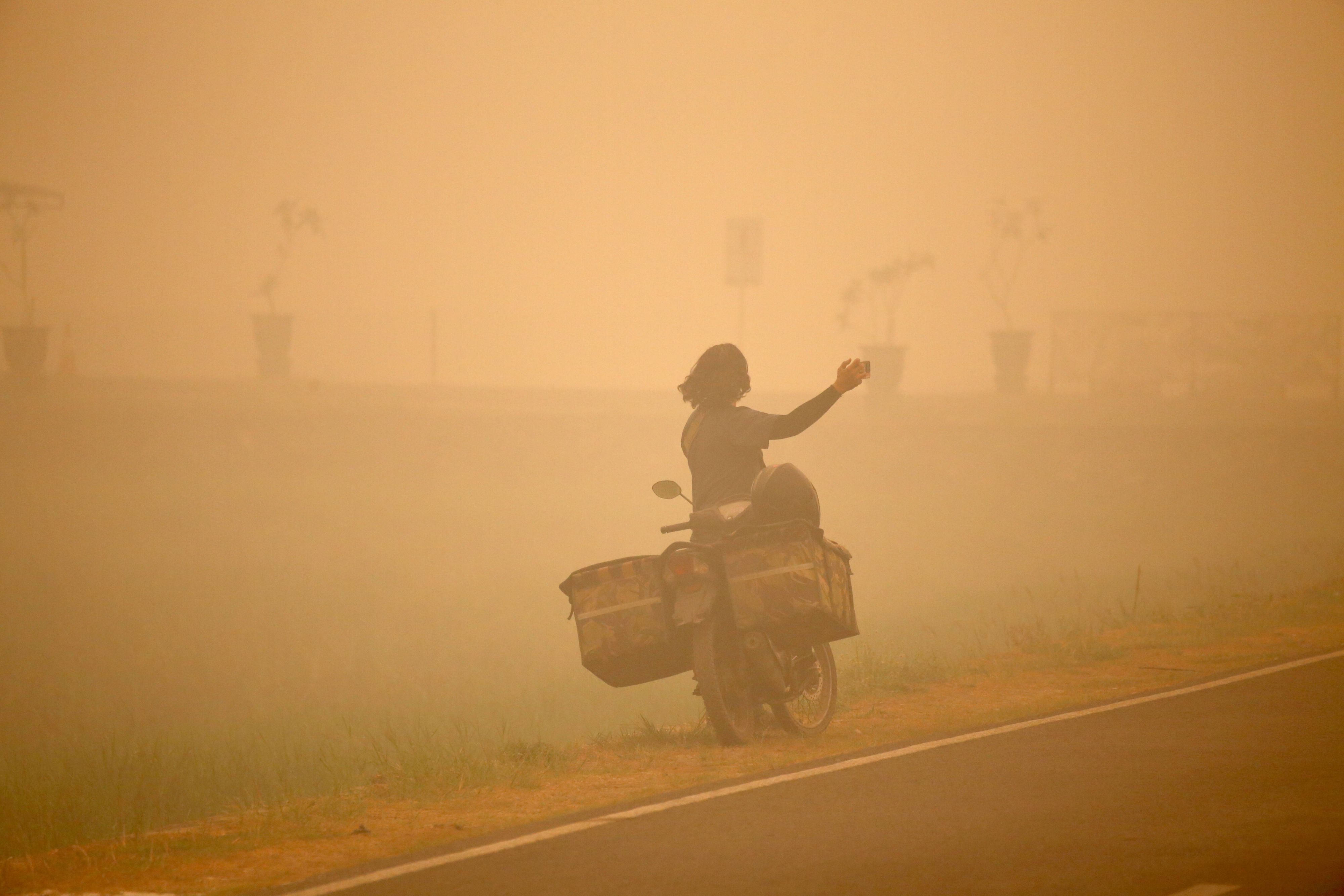 Eine Person macht Fotos inmitten des dichten Dunstes, der durch Wald- und Torfbrände in Palangka Raya, Zentralkalimantan, Indonesien, verursacht wird.