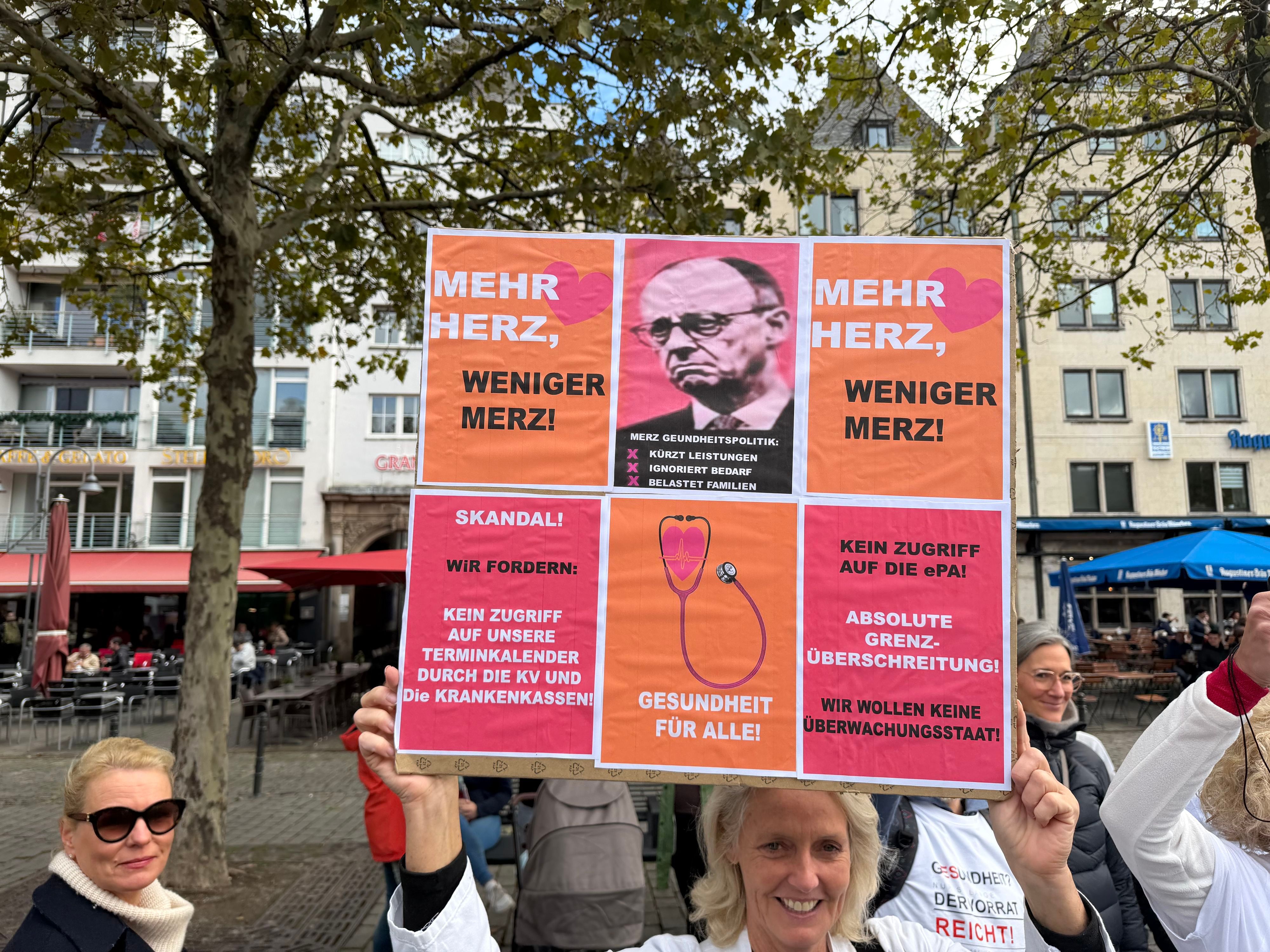 Demonstrierende in Köln machten mit dem Plakat „Mehr Herz, weniger Merz!“ und Forderungen gegen den Zugriff auf die elektronische Patientenakte (ePA) ihrem Ärger über die aktuelle Gesundheitspolitik Luft.
