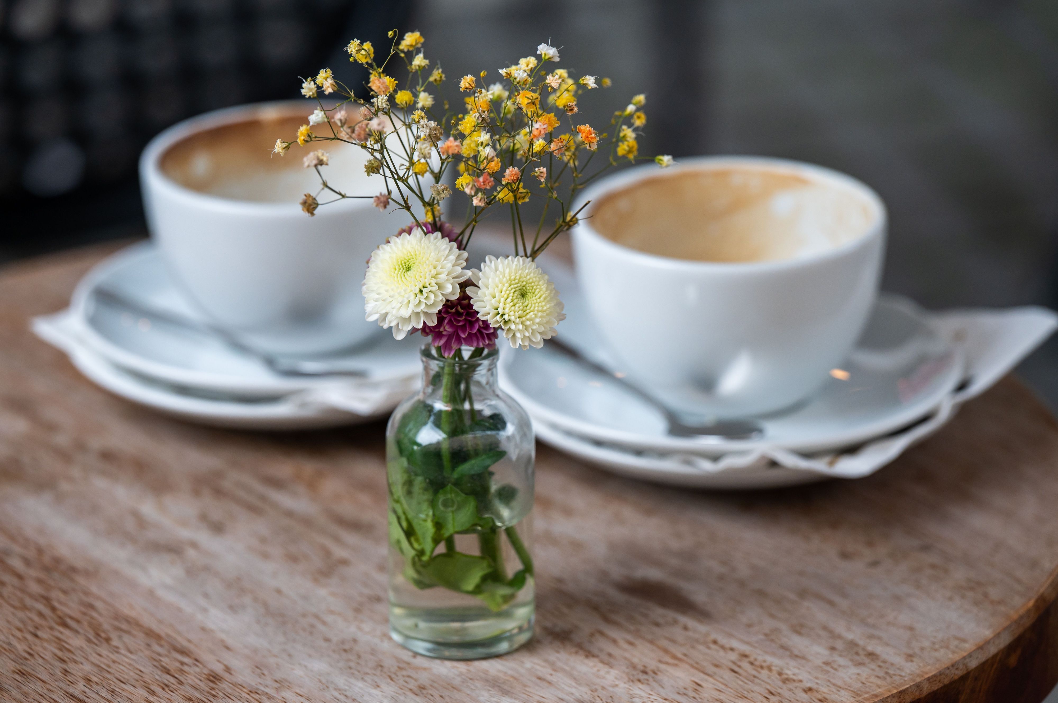 ARCHIV - 16.08.2021, Bayern, München: Eine kleine Vase mit Blumen steht in einem Straßencafe in der Innenstadt auf einem Tisch vor zwei benutzten, leeren Kaffeetassen. (zu dpa: «Sporadisch Café-Small-Talk: Sind wir nur noch Pseudofreunde?») Foto: Peter Kneffel/dpa +++ dpa-Bildfunk +++